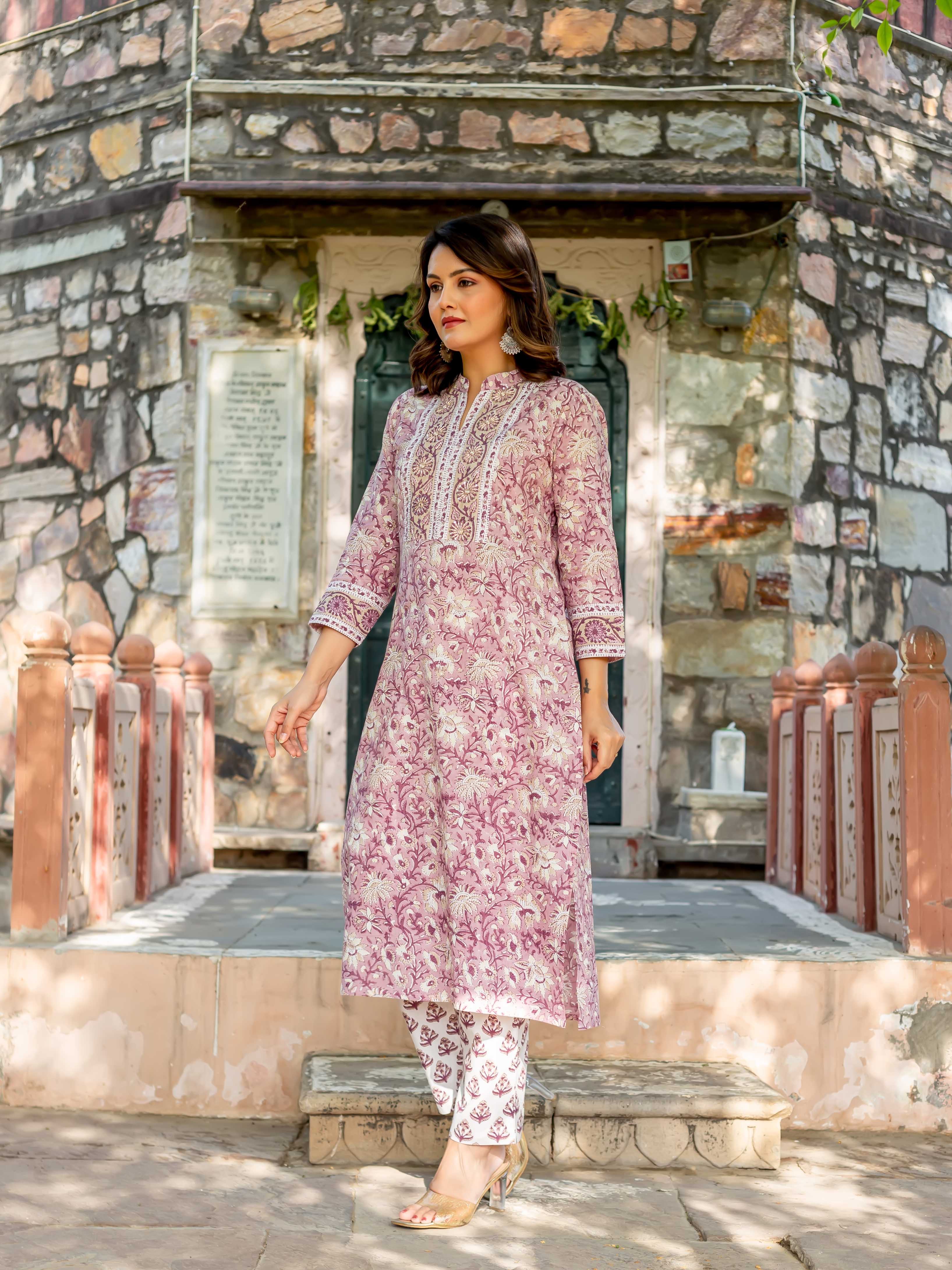 Woman in pink and white hand-block-printed cotton kurta with floral patterns and white trousers.