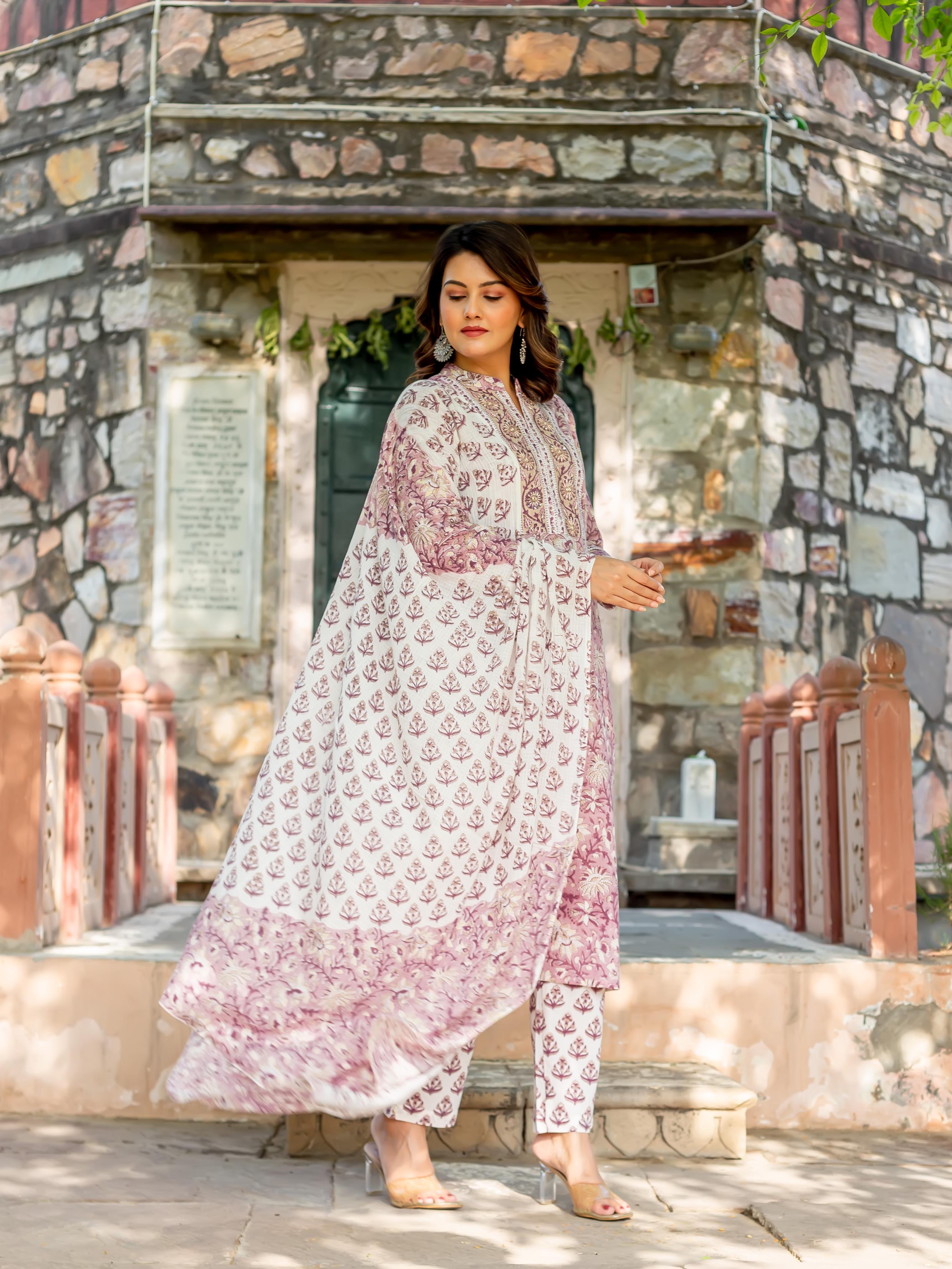 Woman wearing white hand-block-printed old rose kurta set with flowing dupatta, full view.