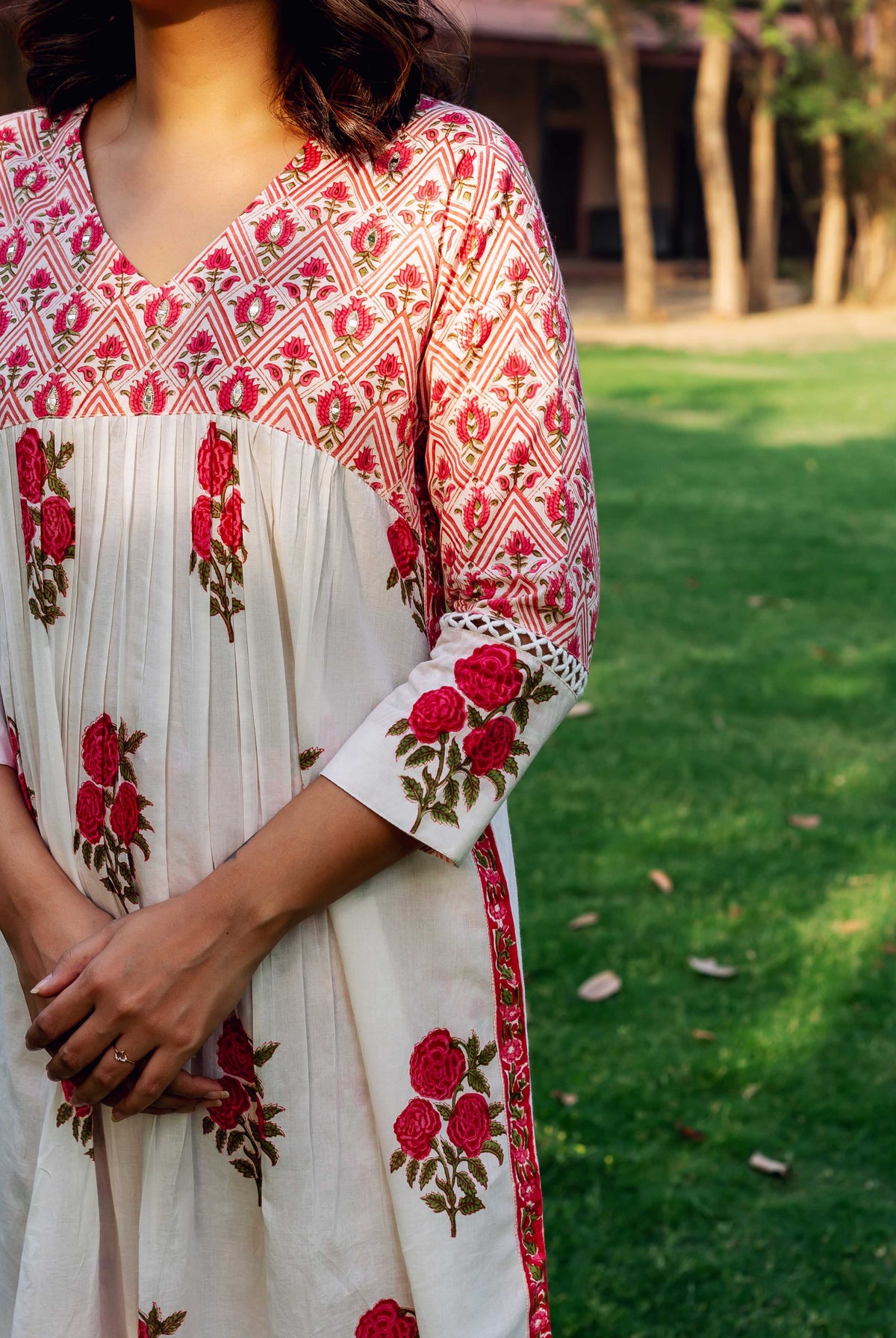 Woman wears white and red hand-block printed cotton kurta with pleated body and rose motif.