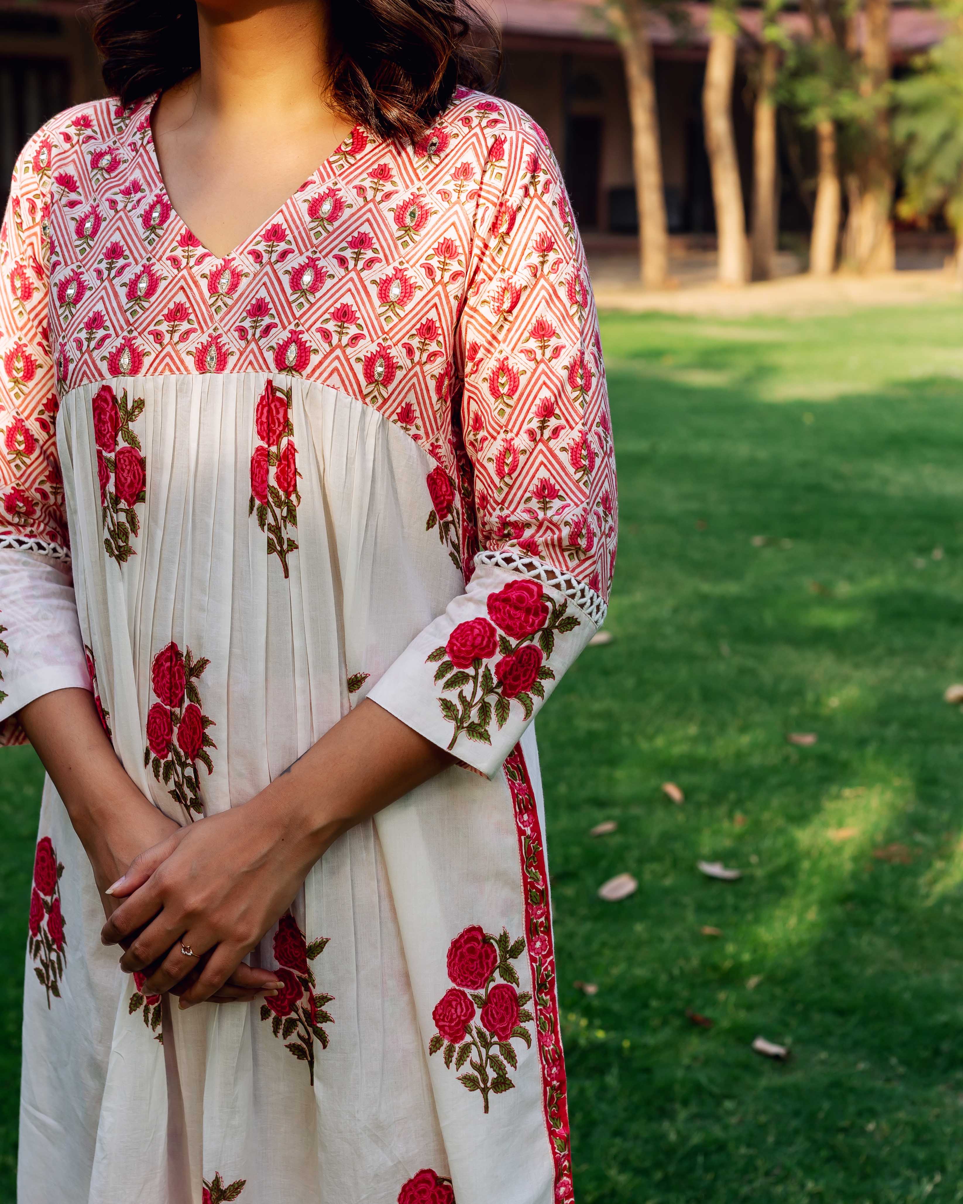 Woman wears white and red hand-block printed cotton kurta with pleated body and rose motif.