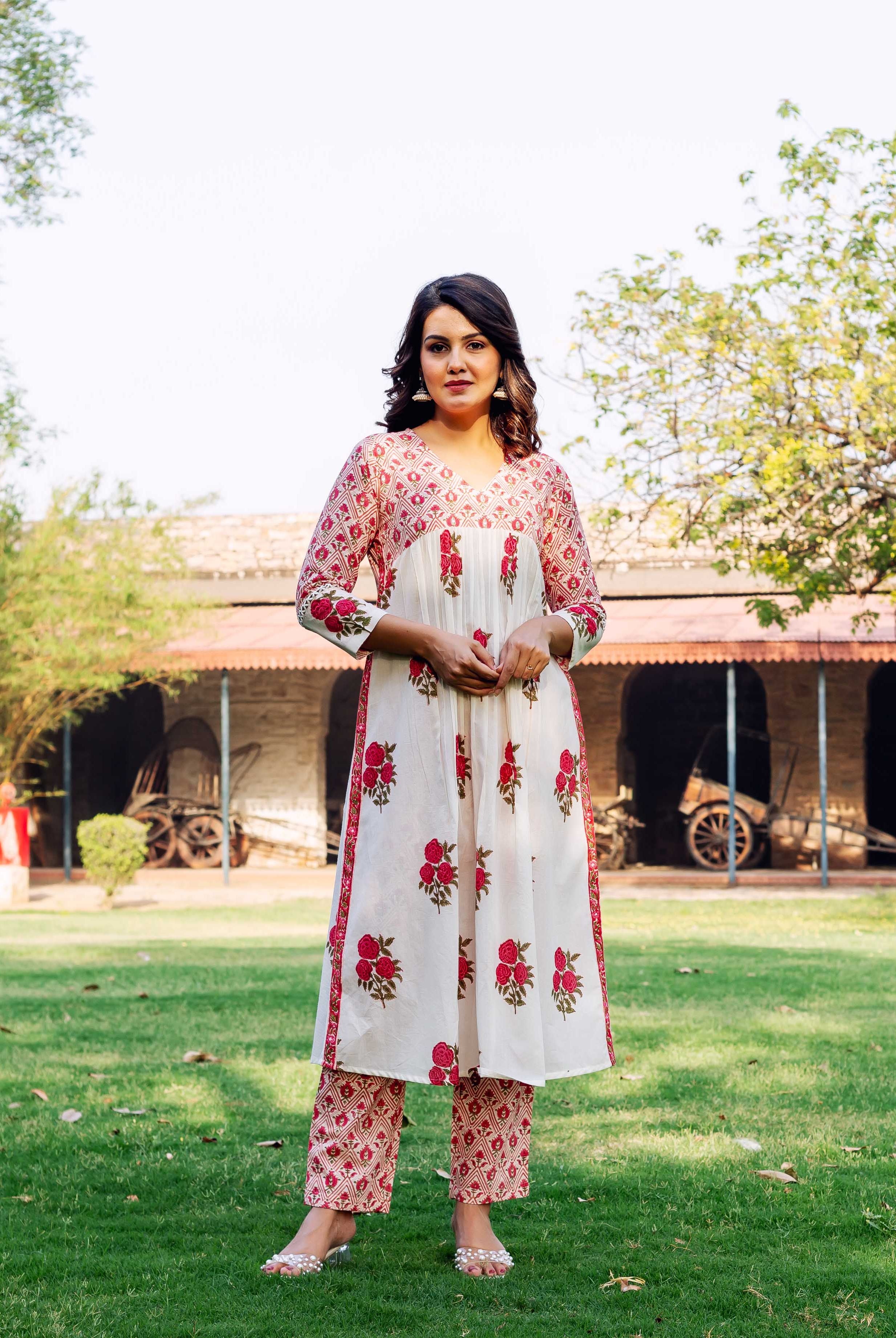 Female model in white cotton kurta and pants with red hand-block floral and geometric prints.