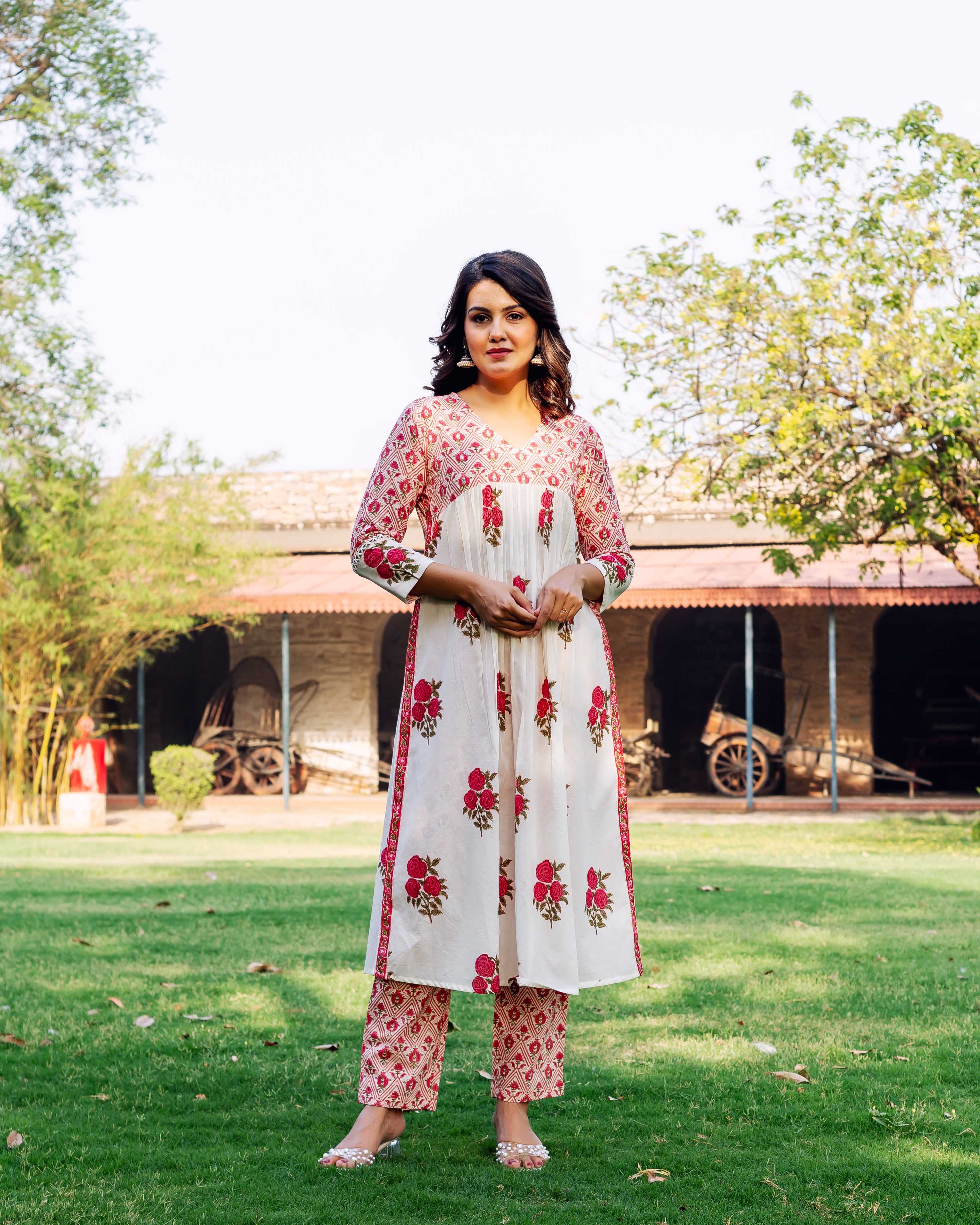 Female model in white cotton kurta and pants with red hand-block floral and geometric prints.