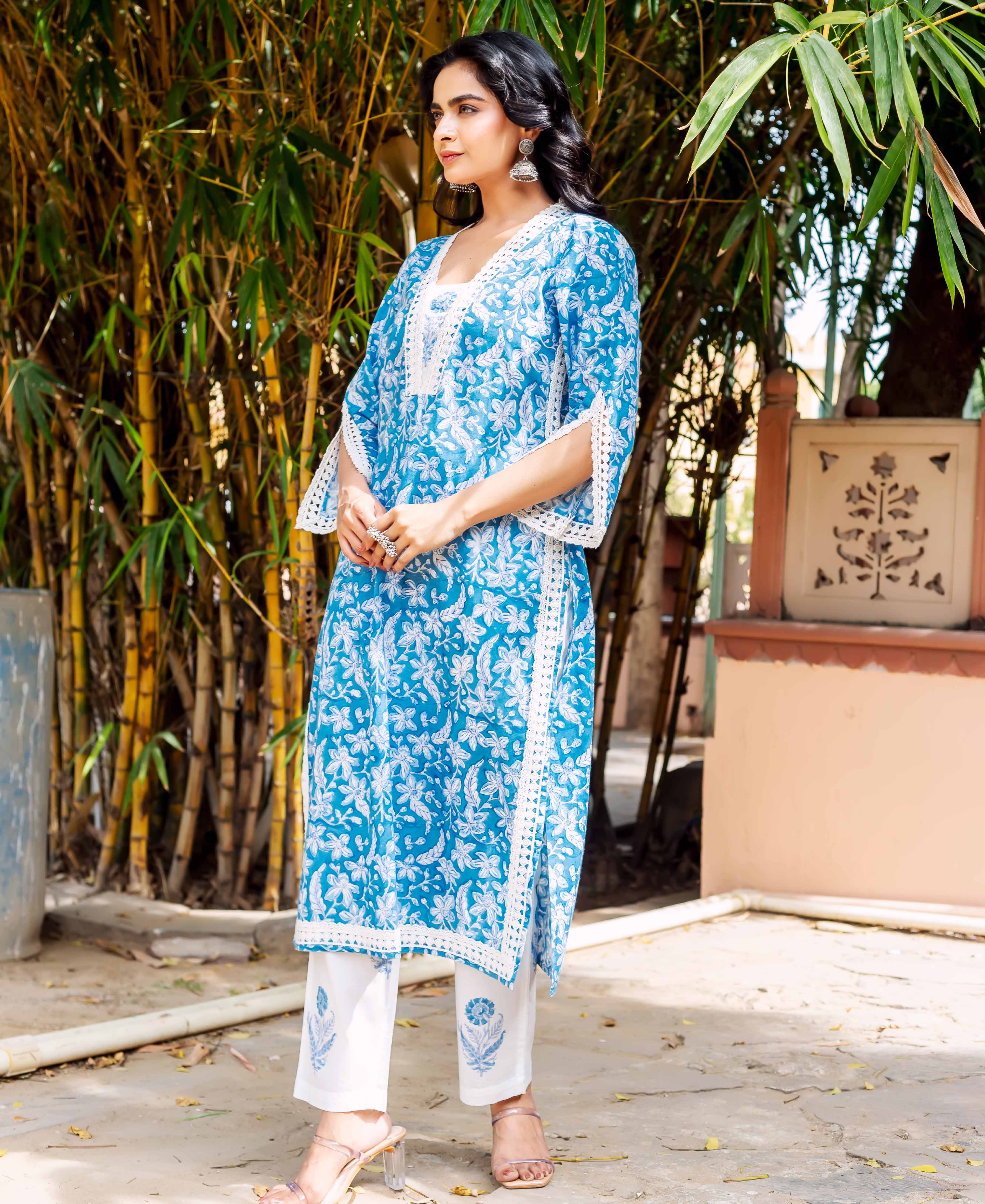 Model in a blue floral cotton kurta with white lace trim and white patterned pants.