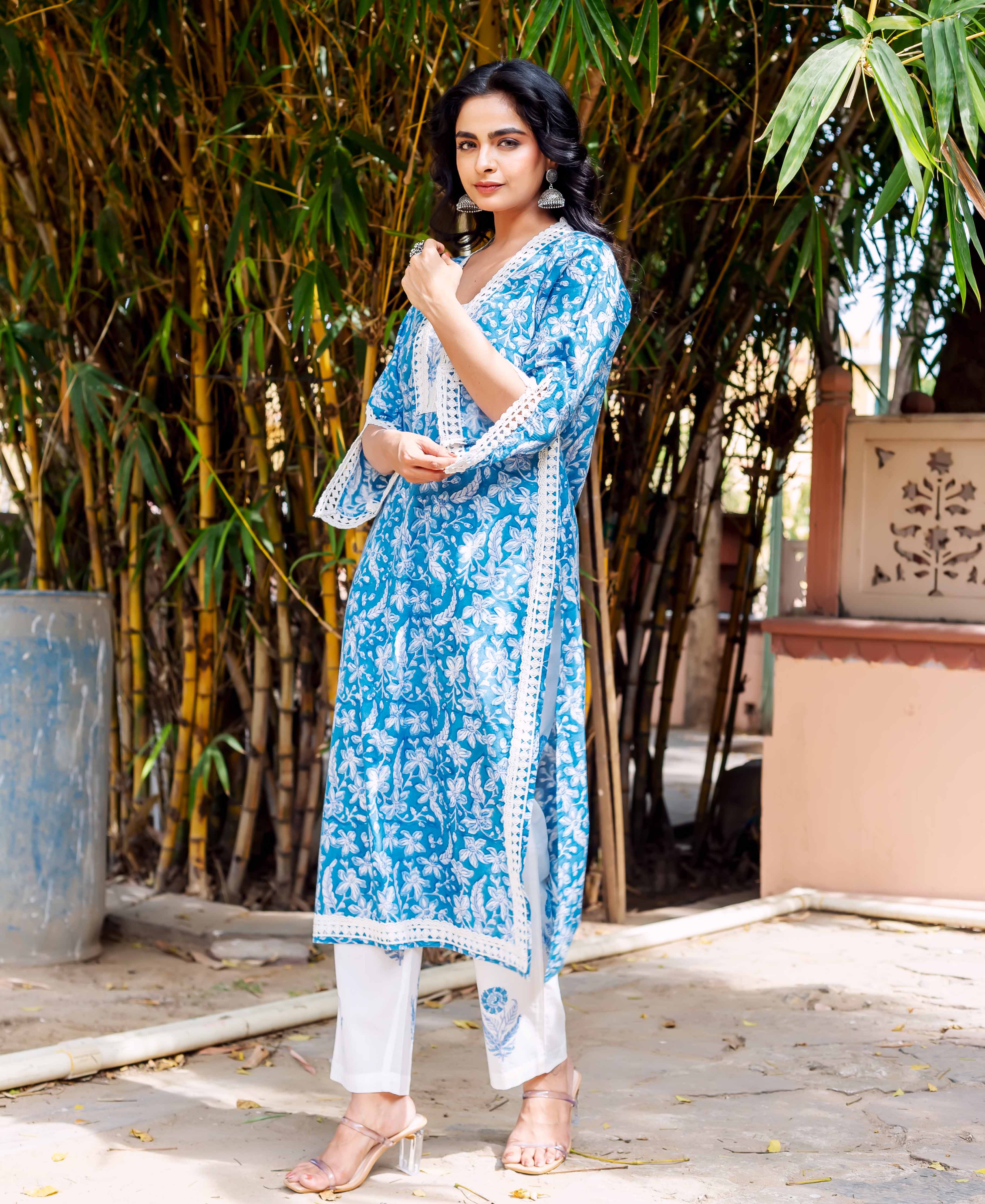 Front view of model in blue block-printed floral cotton kurta with lace detailing and white bottoms.