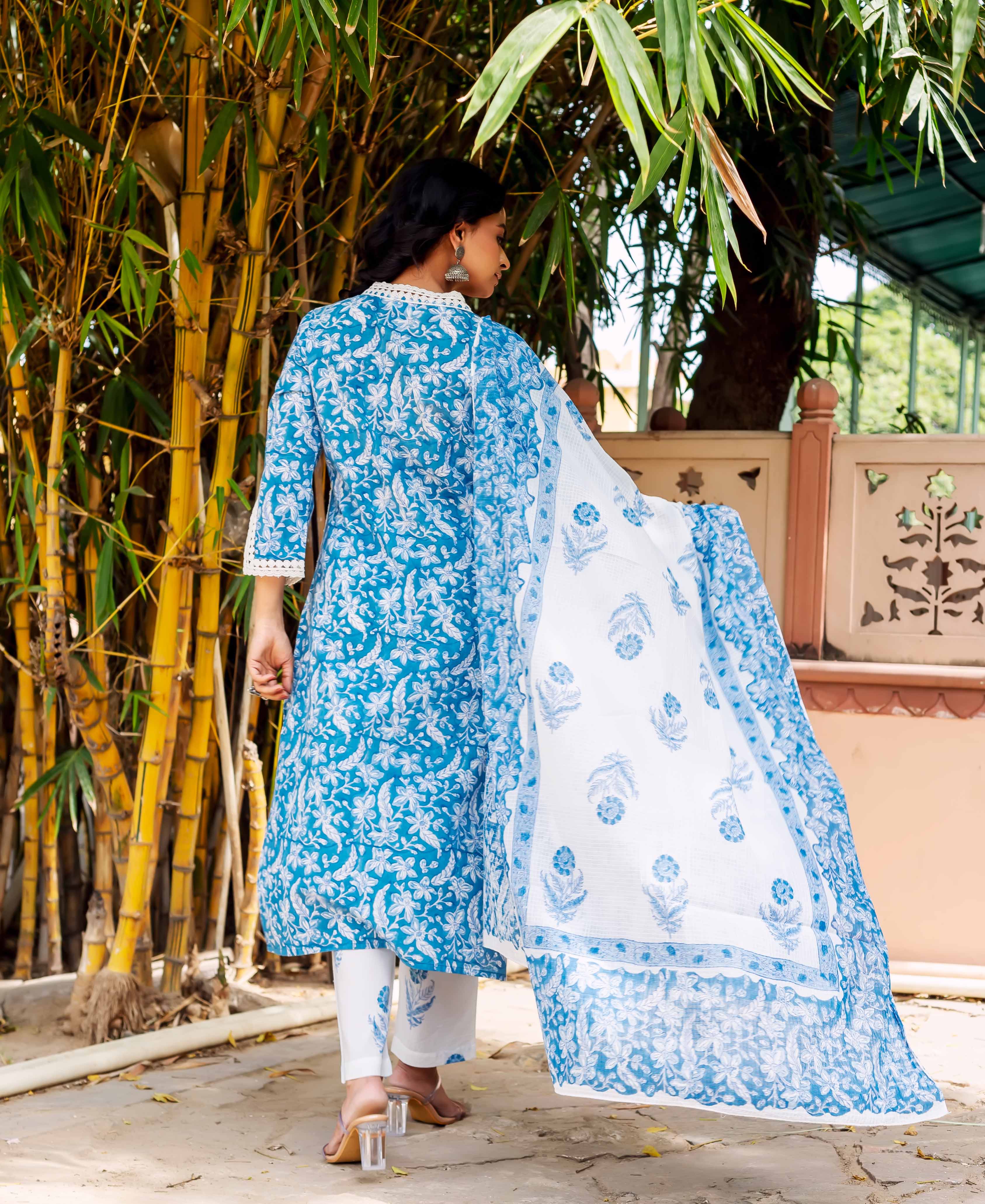 Back view of model in blue floral hand-block-printed kurta set with white lace and dupatta.