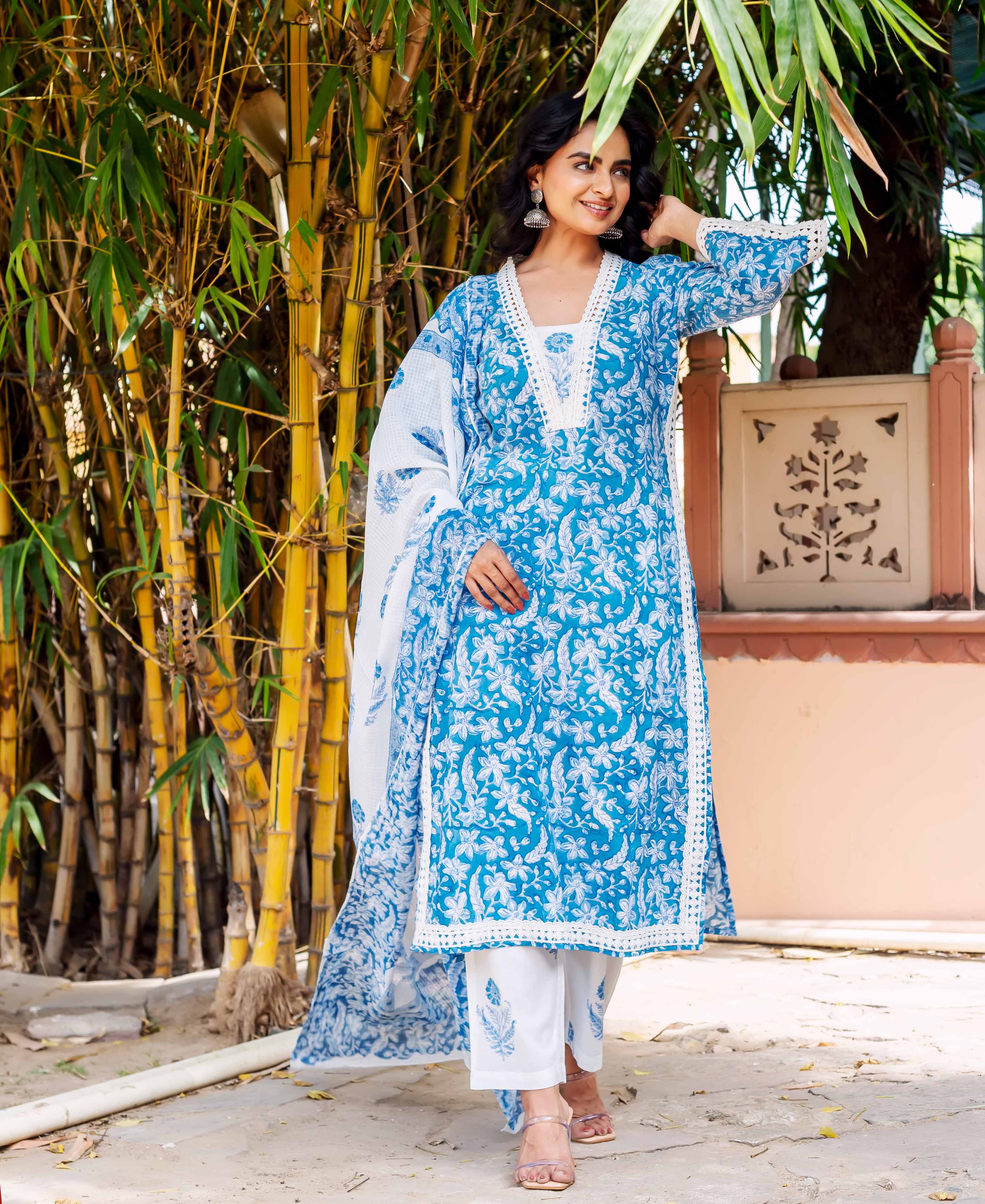 Full-length front view of model wearing blue floral lace kurta, white pants, and dupatta.