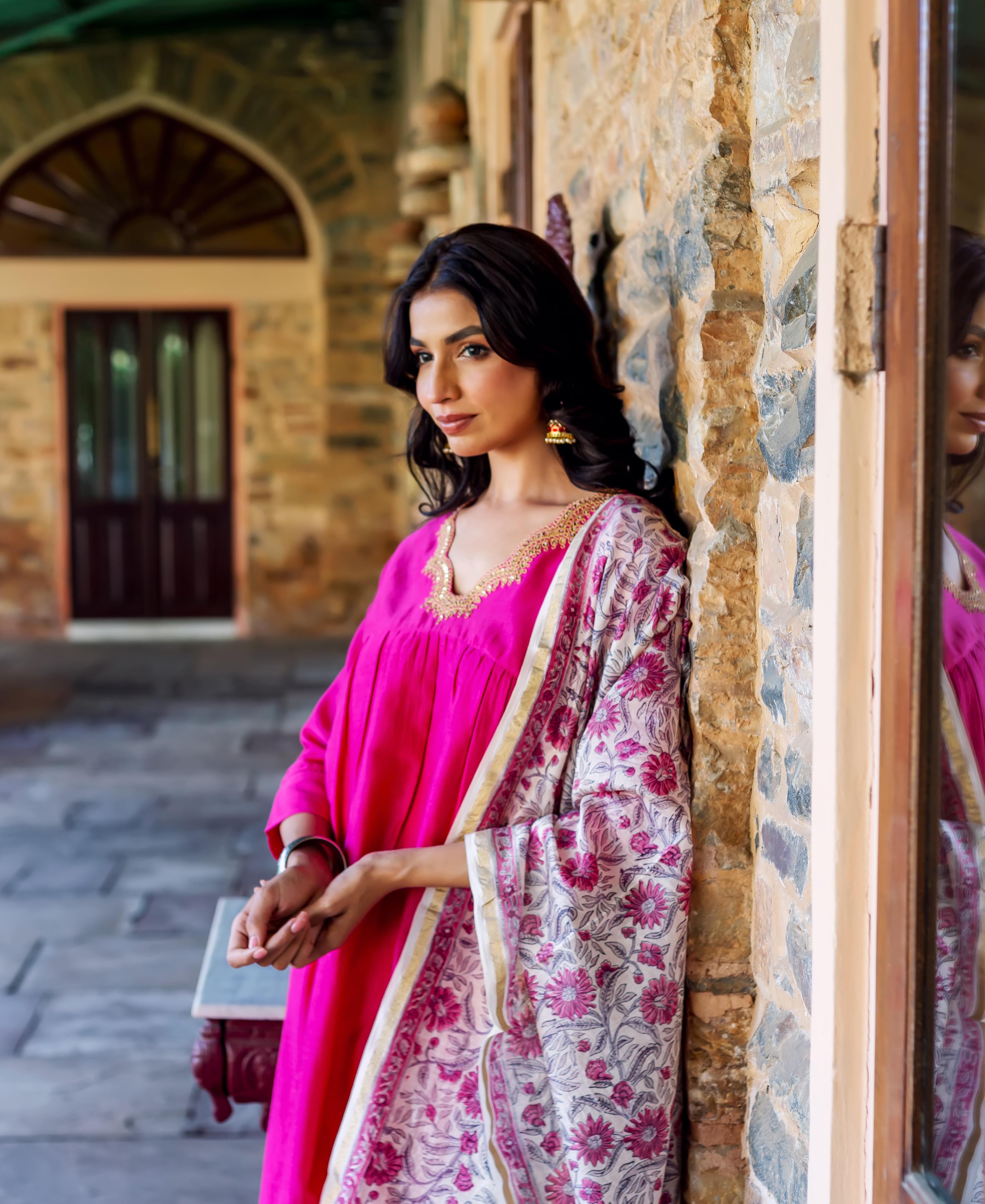 Model in radiant pink Chanderi silk kurta with gold embroidered neck and floral block-printed dupatta.