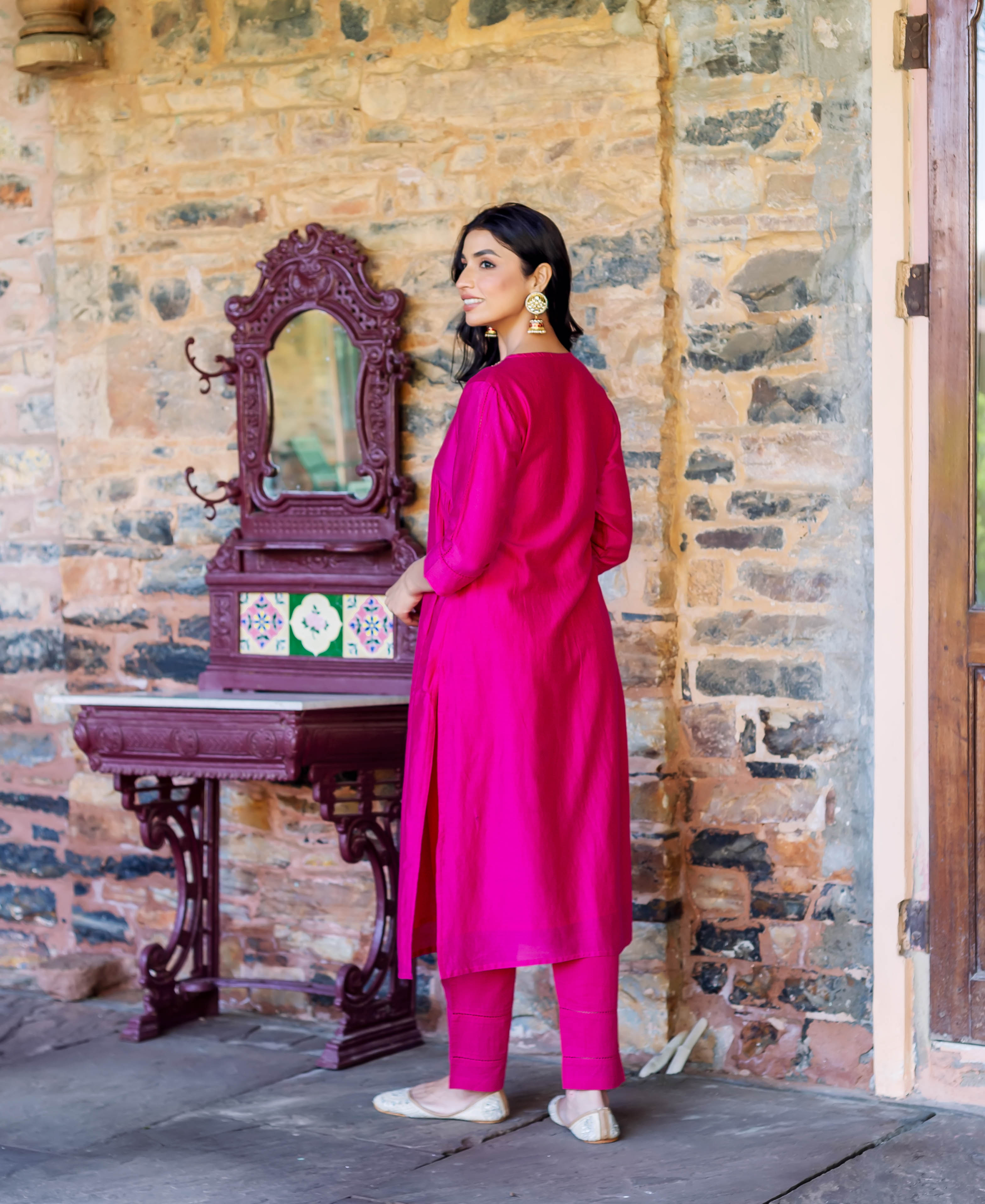 Rear side view of a woman in a vibrant radiant pink solid kurta set.