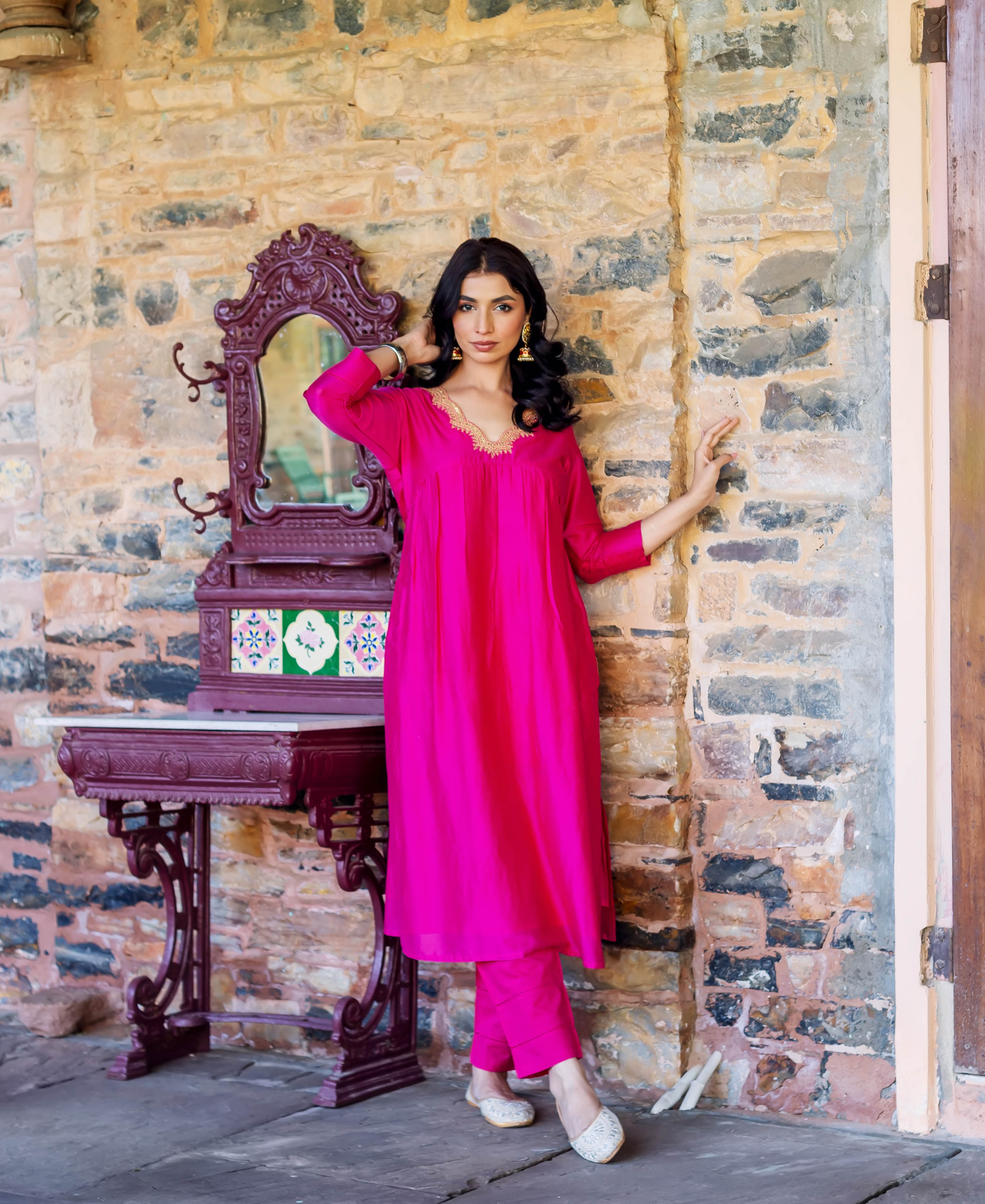 Model in radiant pink chanderi silk kurta and pants with golden embroidered neckline.