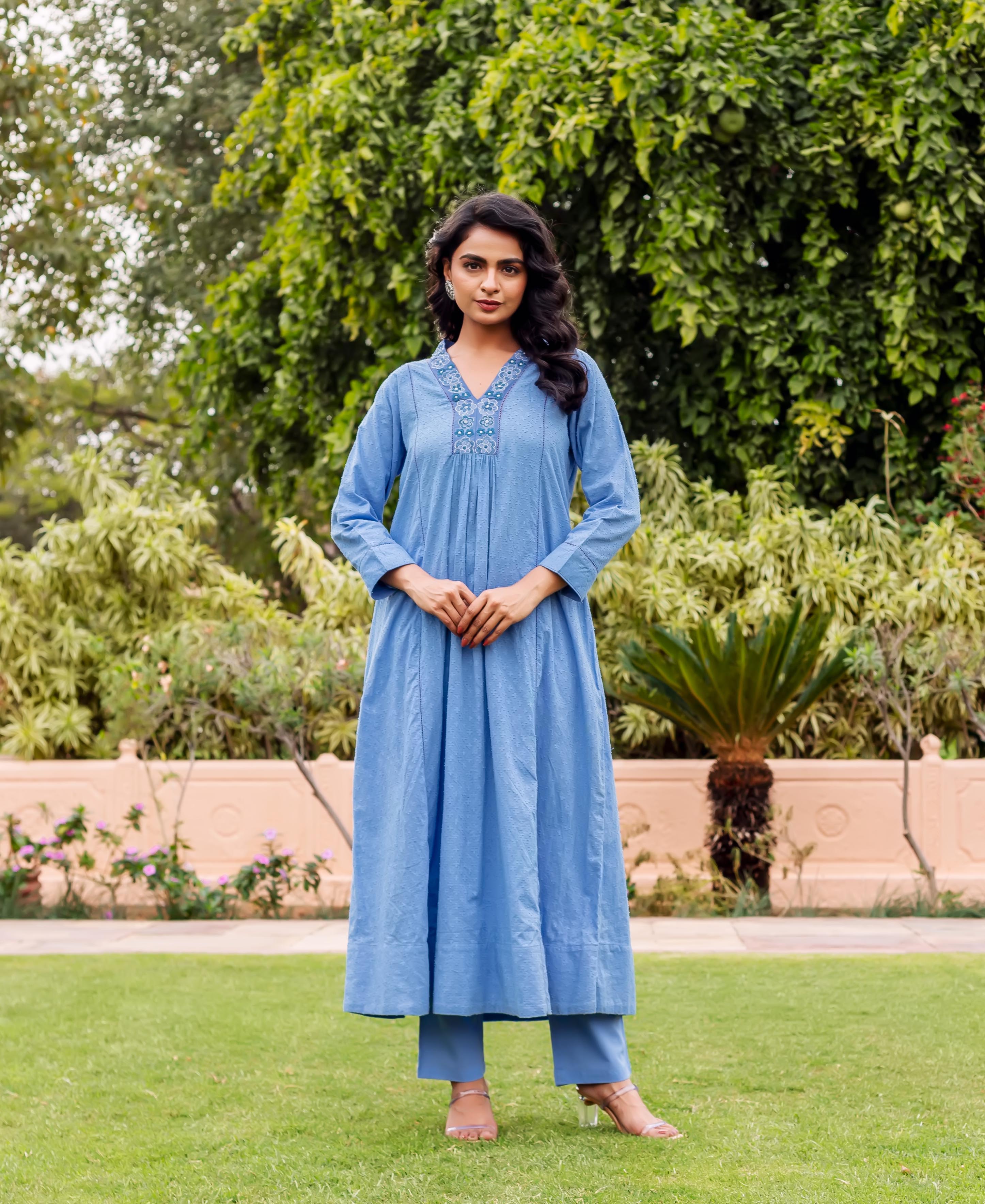 Model wearing a sky blue Anarkali kurta and matching pants with an embroidered V-neck.