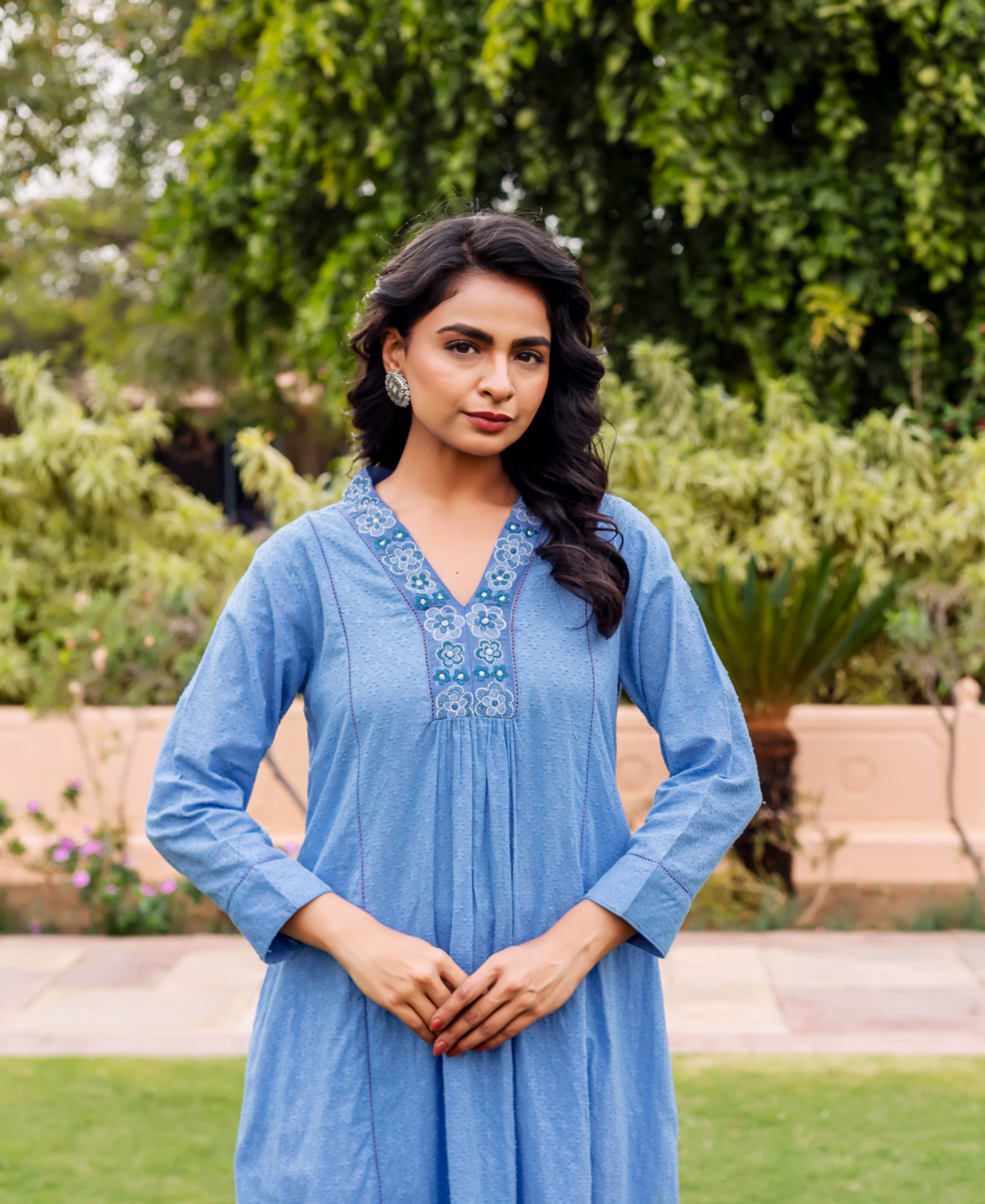 Front view of a model wearing a sky blue Anarkali kurta with blue floral embroidery.