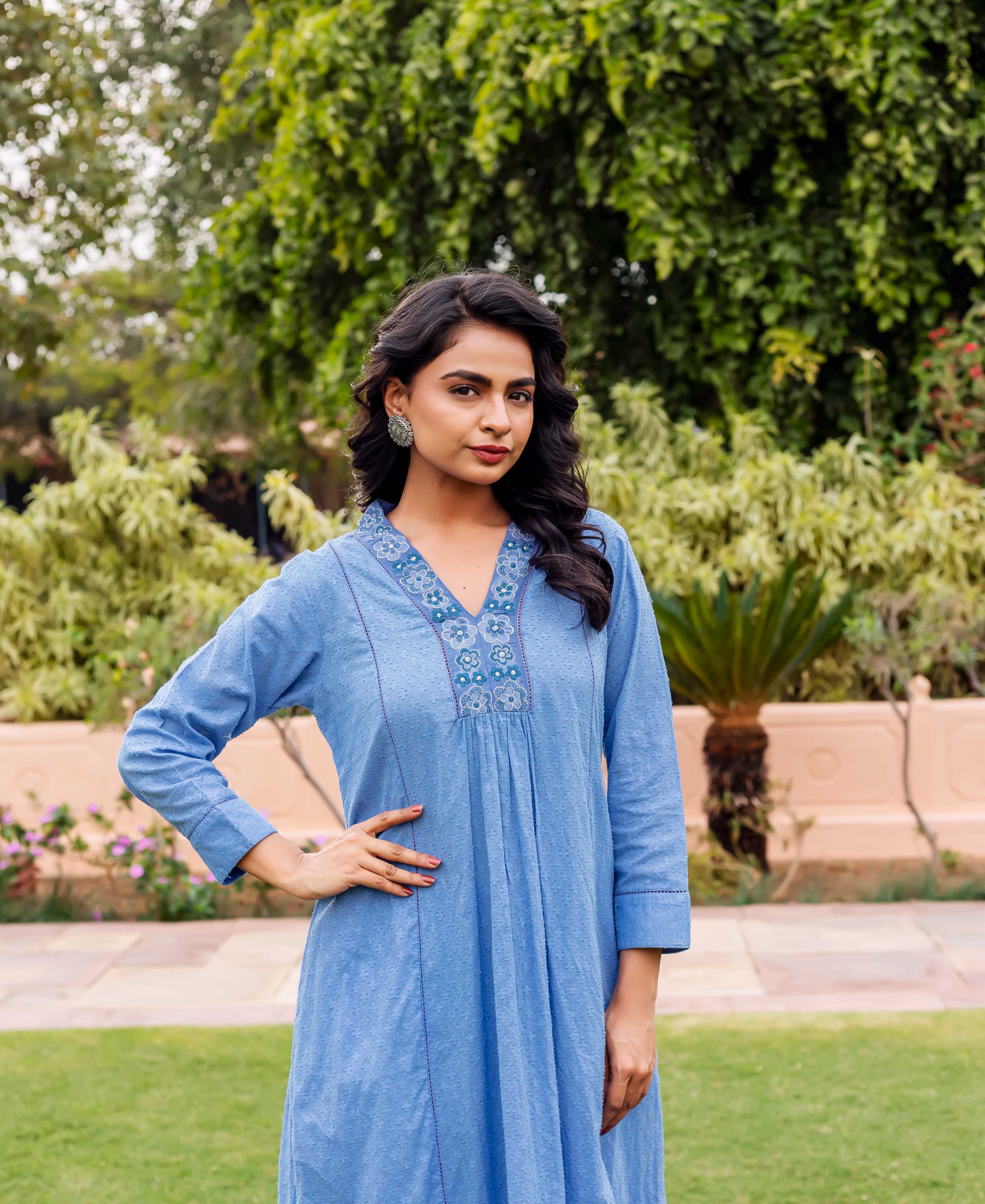 Woman wears a sky blue cotton Anarkali kurta with floral patterned V-neck and subtle white dots.