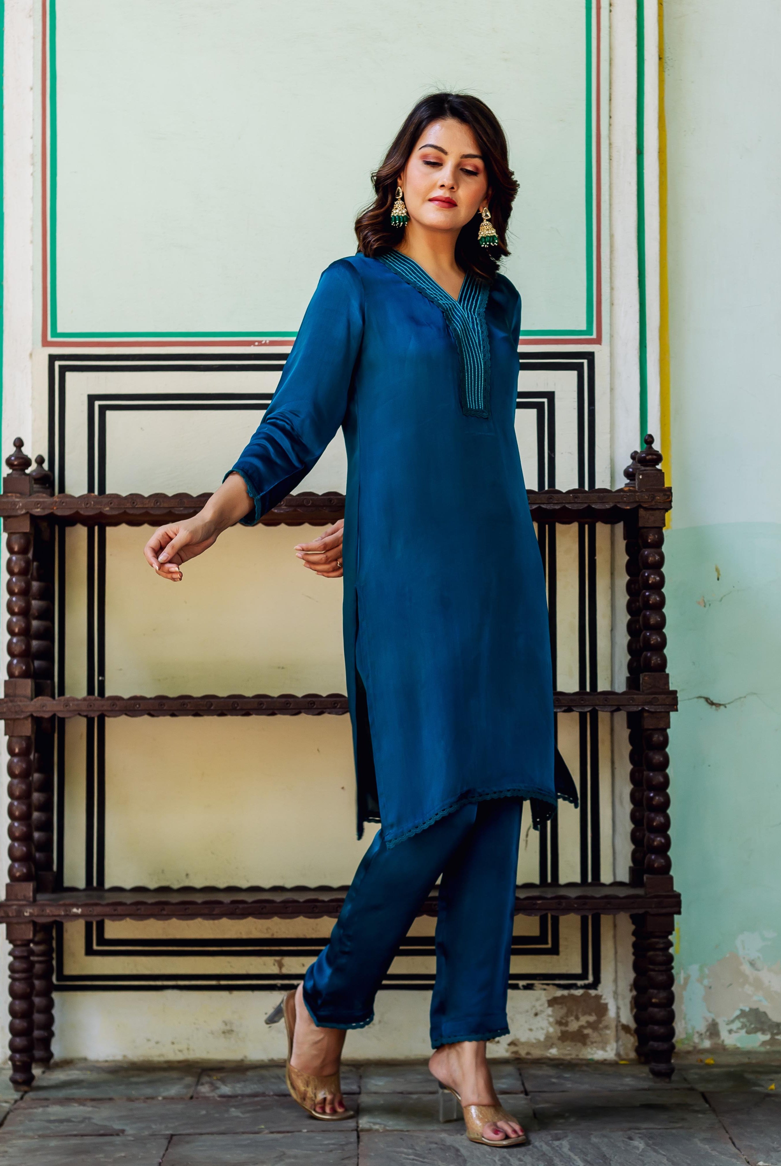 Standing model in a royal blue satin kurta set with elegant striped V-neckline.