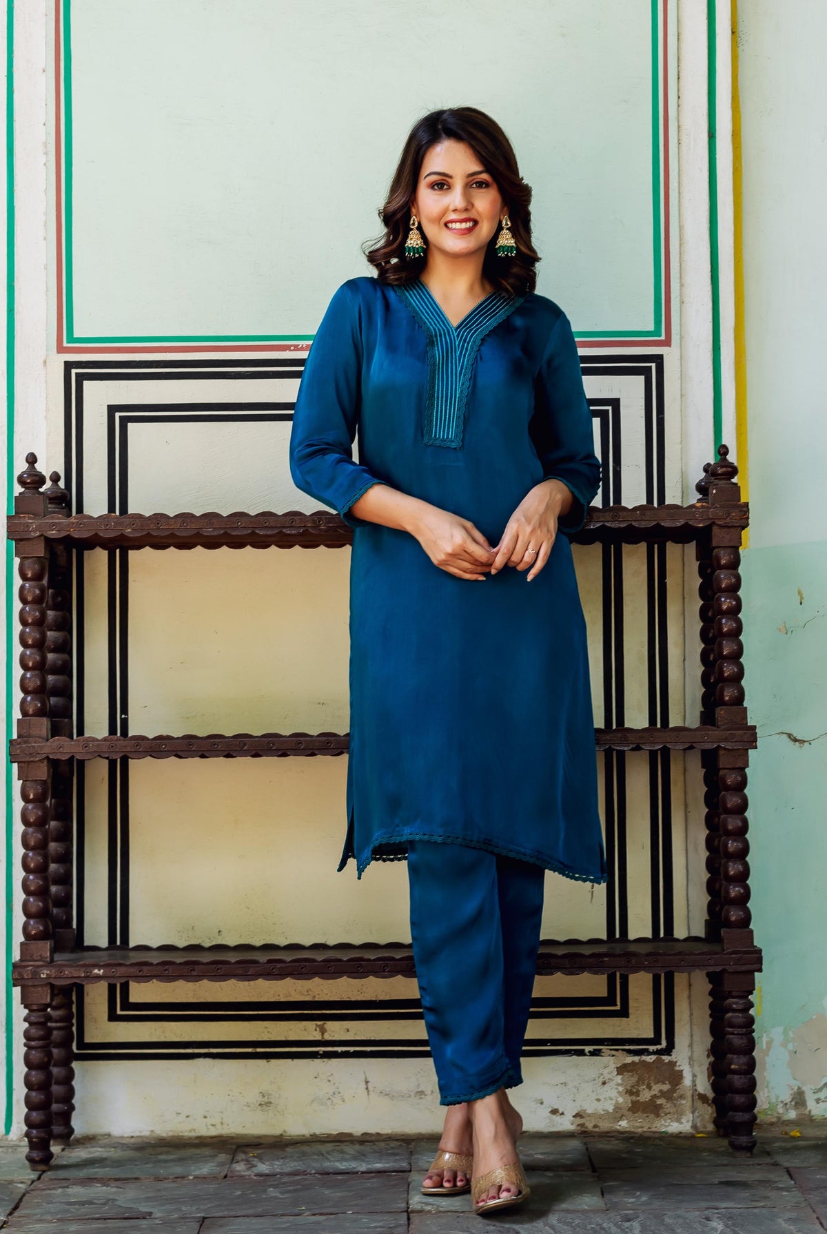 Smiling woman modeling a royal blue satin kurta set with detailed V-neckline.