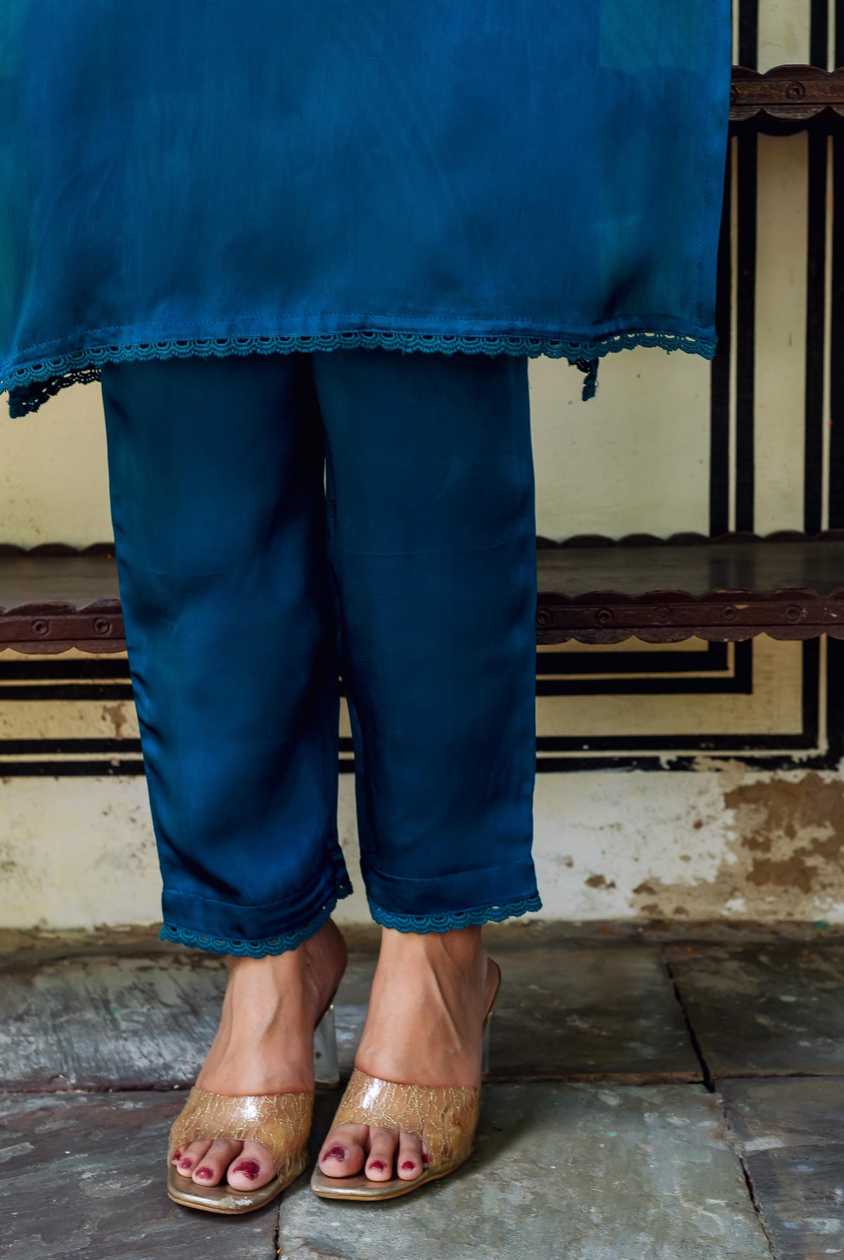 Model in royal blue satin kurta and pants with lace trim, wearing golden heels.