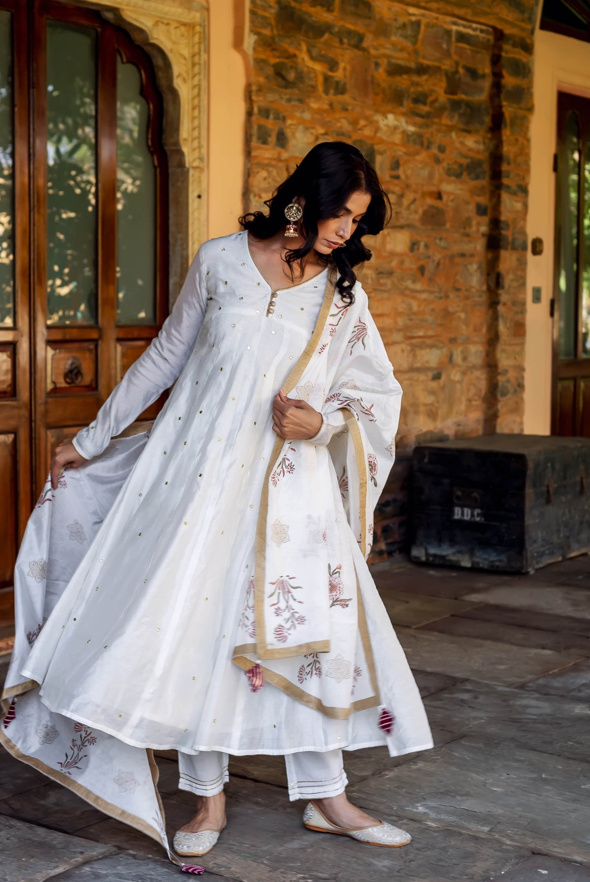 Model wearing white Anarkali kurta, pants, and floral hand-block printed dupatta with golden details.