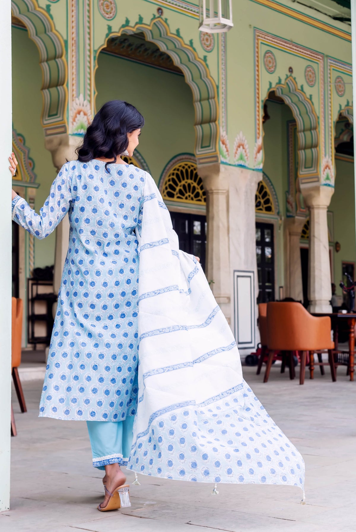 Rear view of model in light blue hand-block printed kurta set and white patterned dupatta.