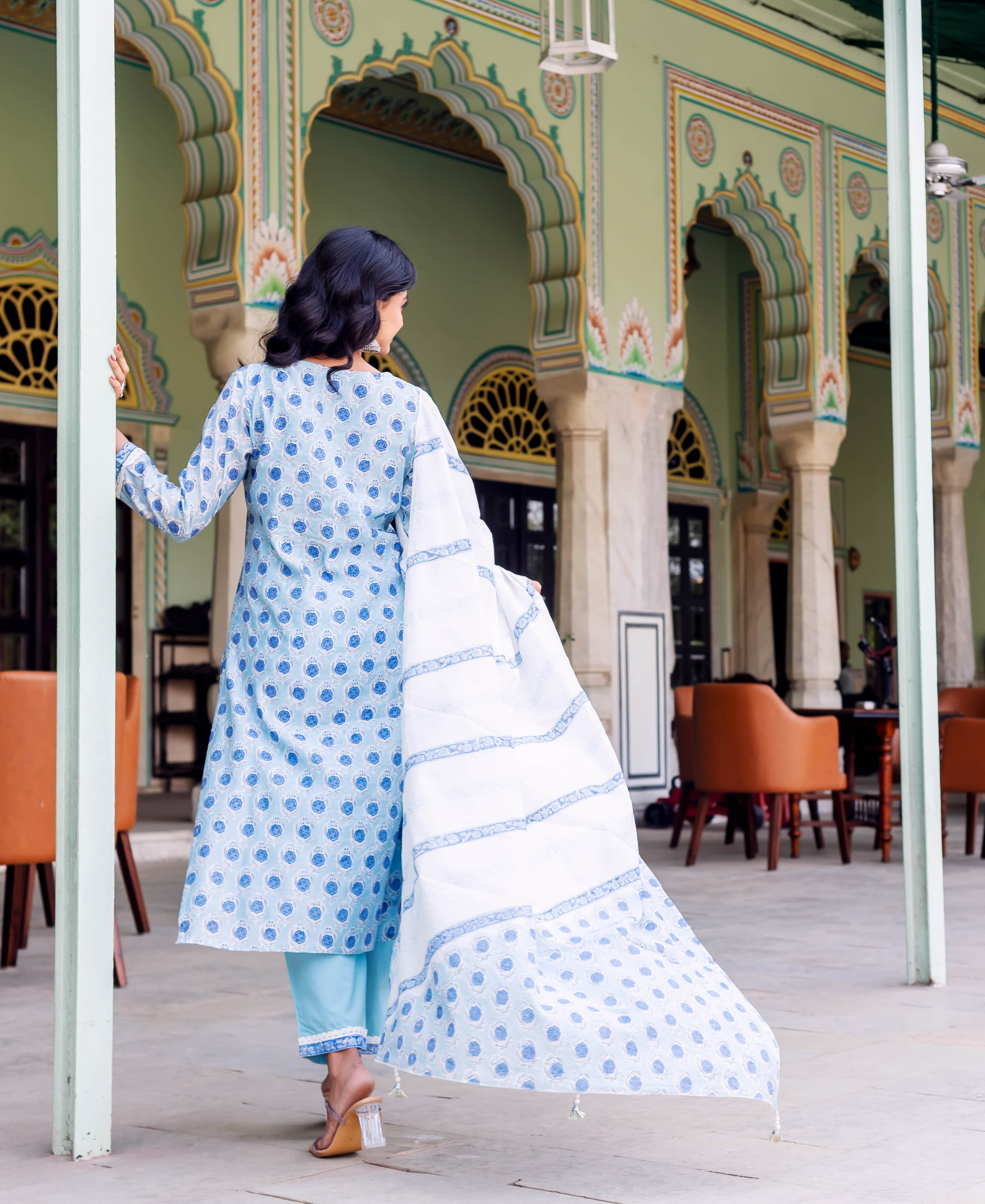 Rear view of model in light blue hand-block printed kurta set and white patterned dupatta.