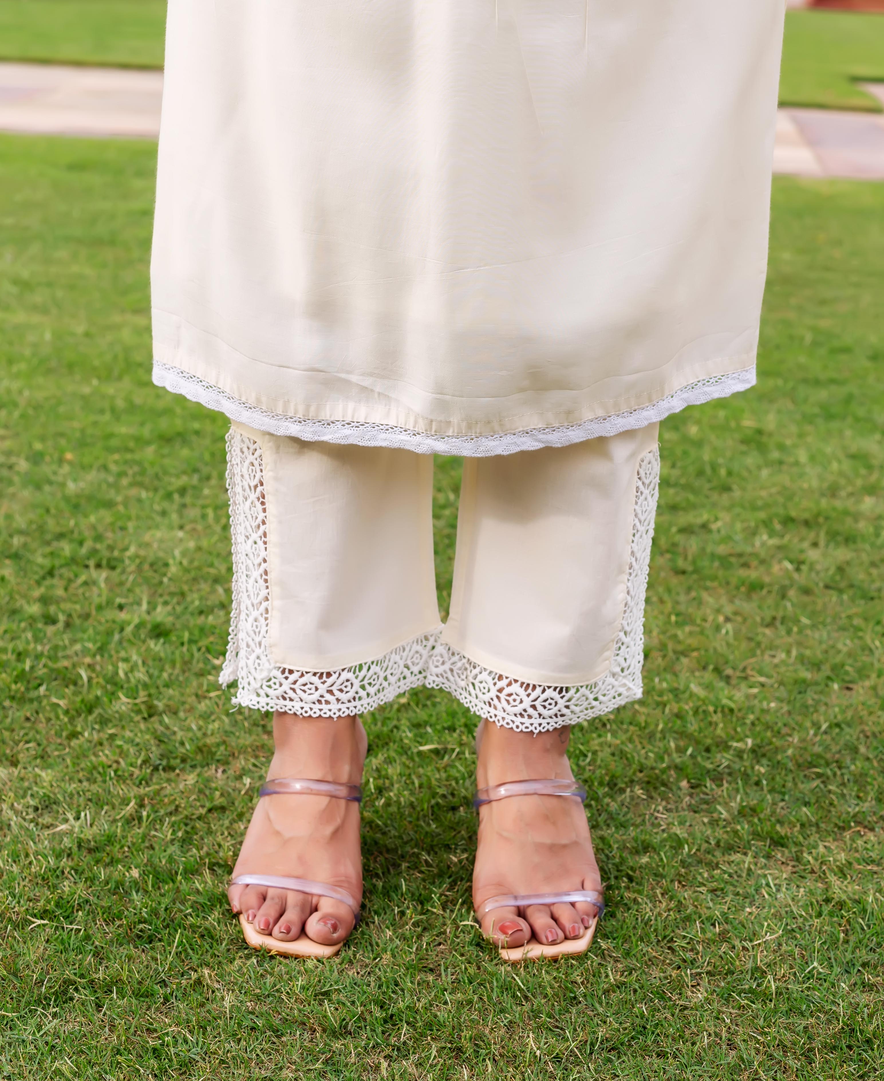 Model in cream kurta with delicate lace hem and matching wide-leg pants with lace.