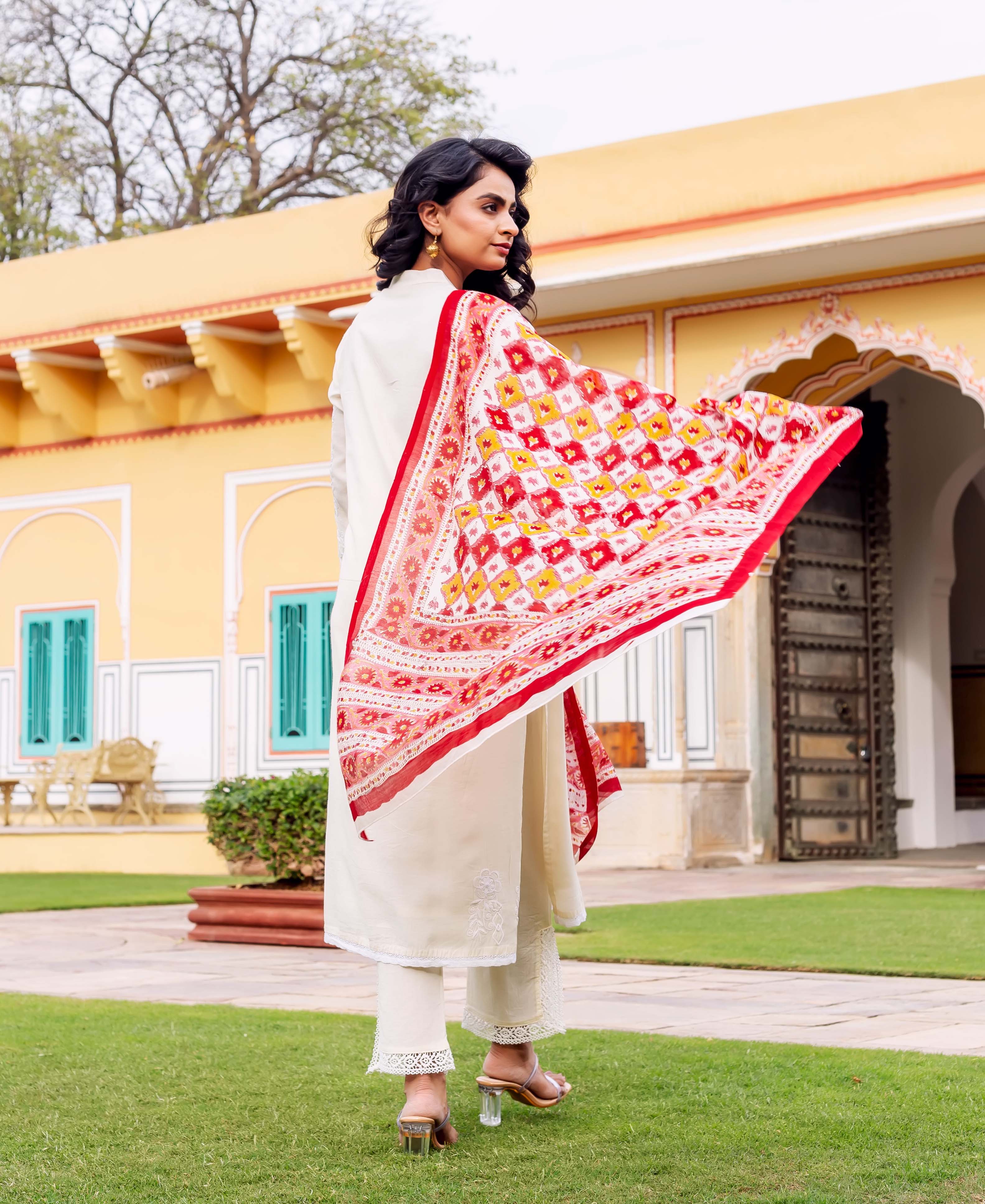 Back view of model in antique white kurta set with red and yellow ethnic print dupatta.