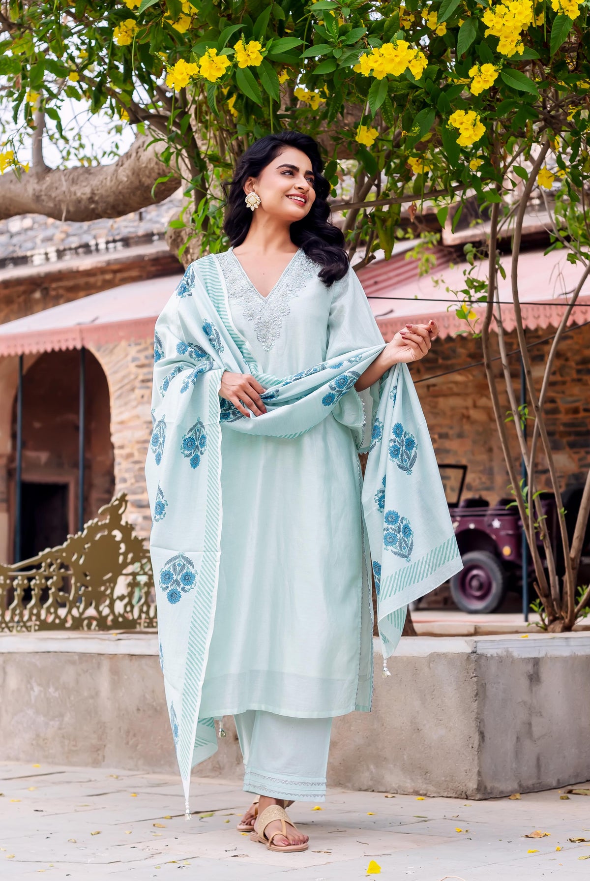Smiling model in mint green hand-block-printed kurta set with blue floral dupatta outdoors.