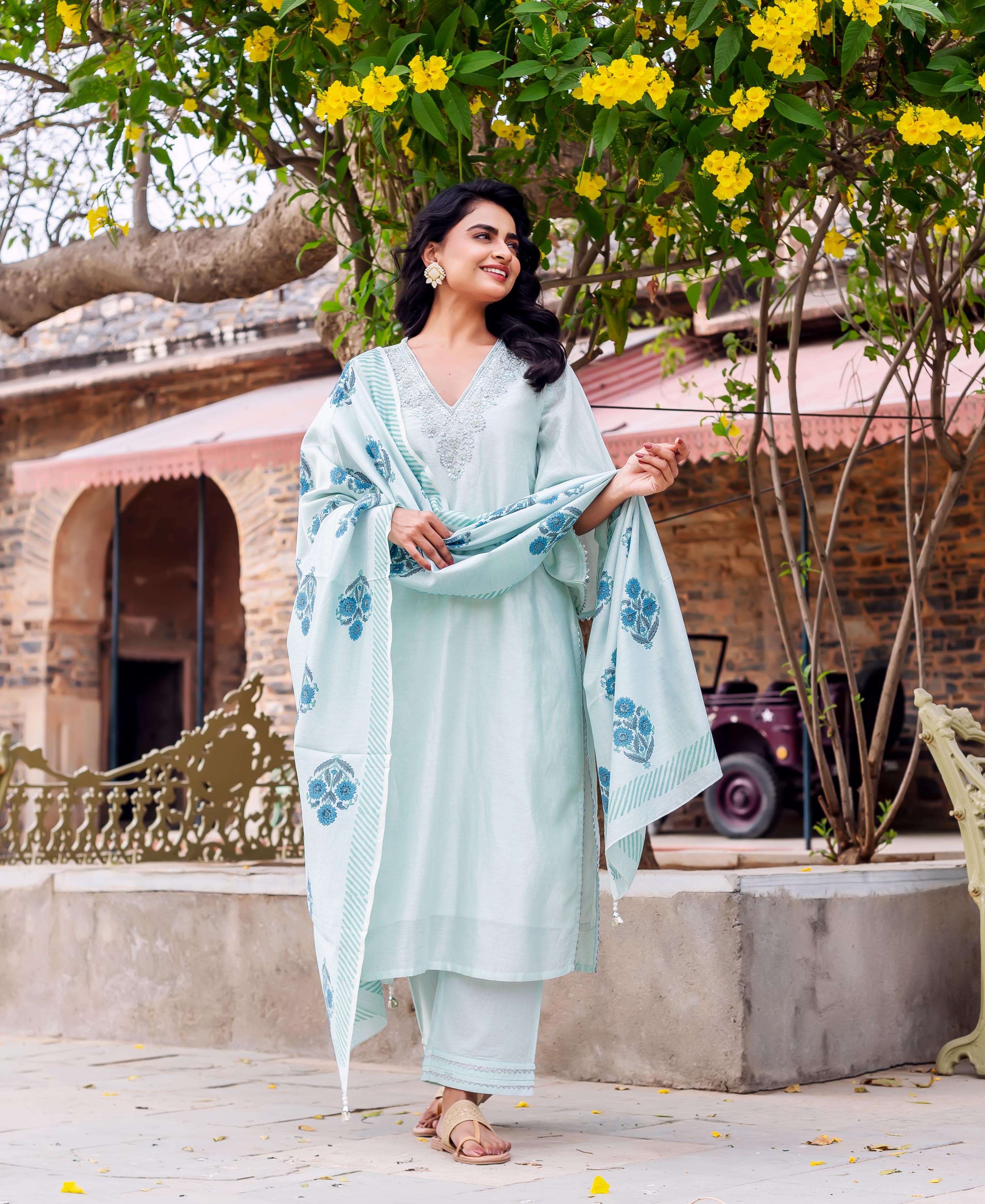 Smiling model in mint green hand-block-printed kurta set with blue floral dupatta outdoors.