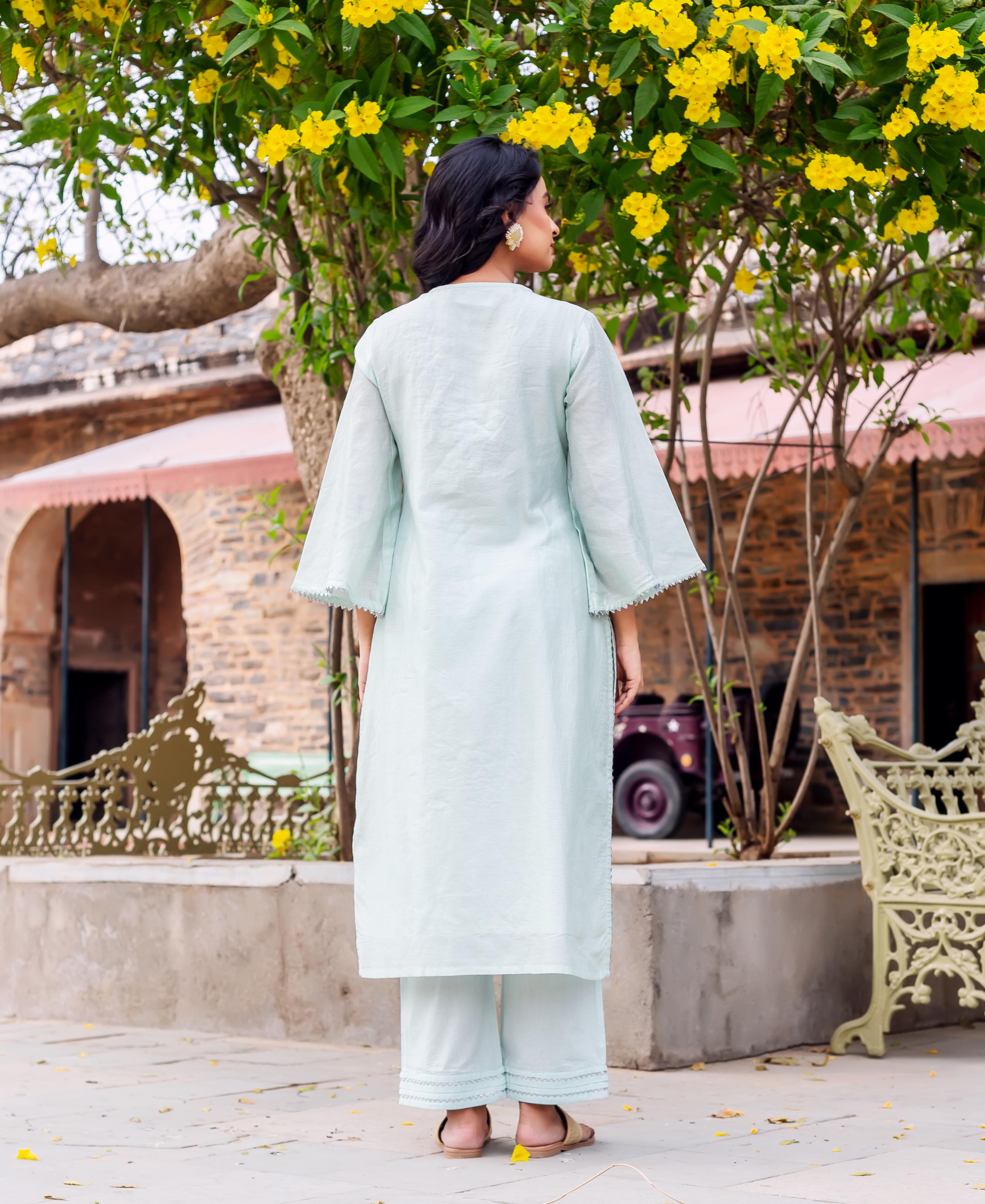 Model from behind wearing a mint Chanderi silk kurta set with scalloped trim and gold earrings.
