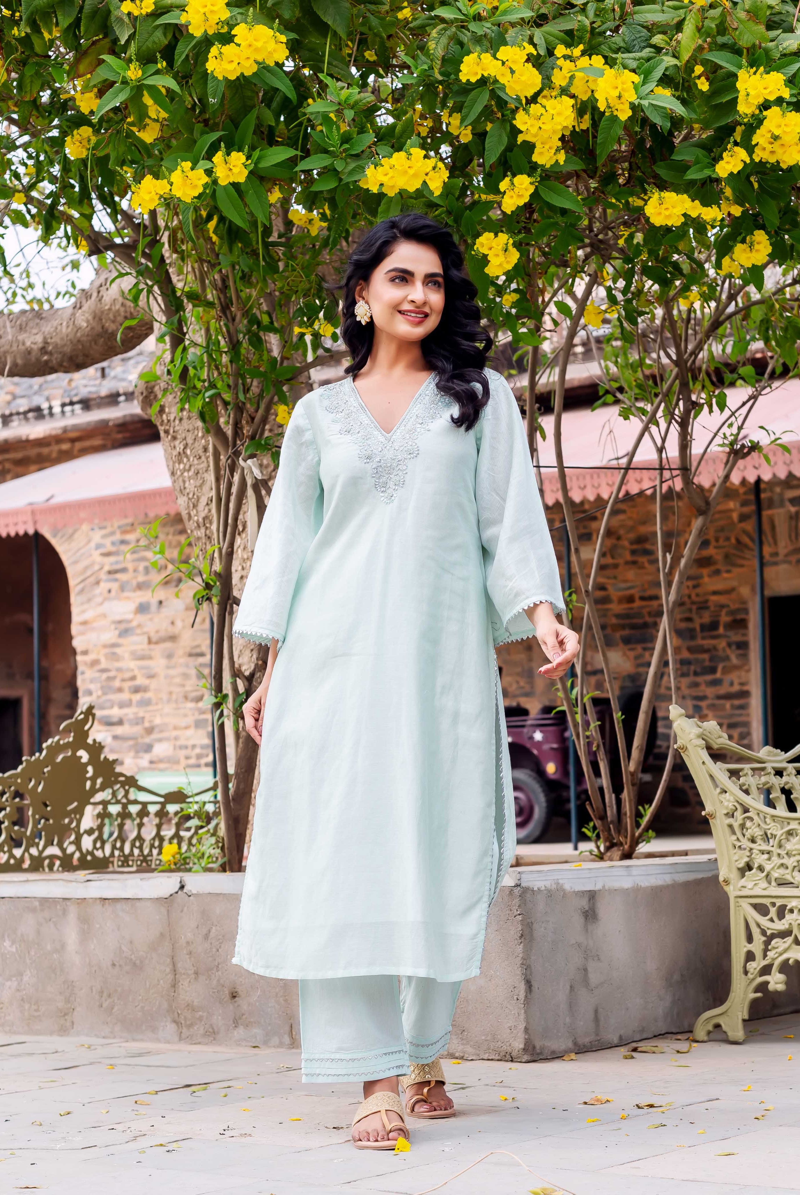Full-body shot of woman in mint green kurta set with embroidered V-neck, walking.
