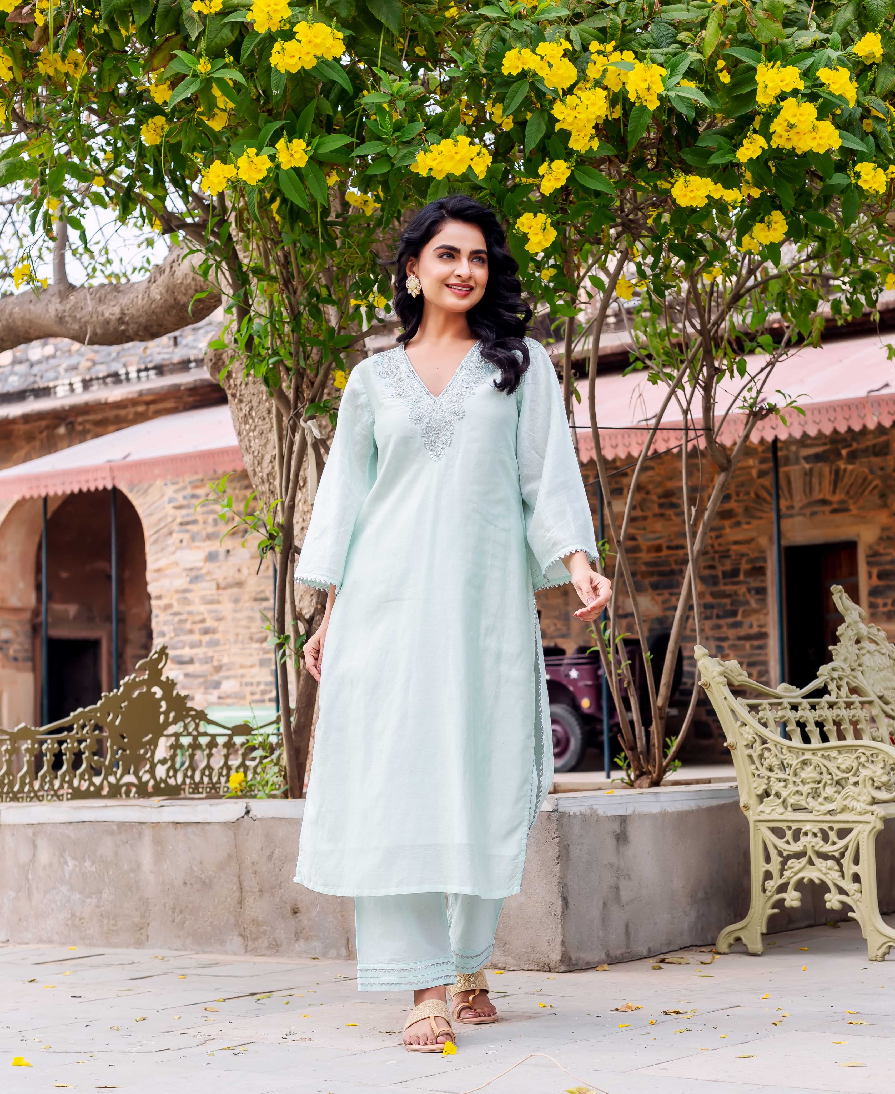 Full-body shot of woman in mint green kurta set with embroidered V-neck, walking.