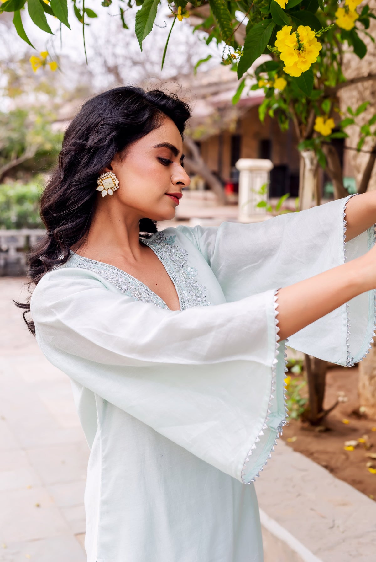 Side view of model in light mint kurta with embroidered V-neck and bell sleeves.