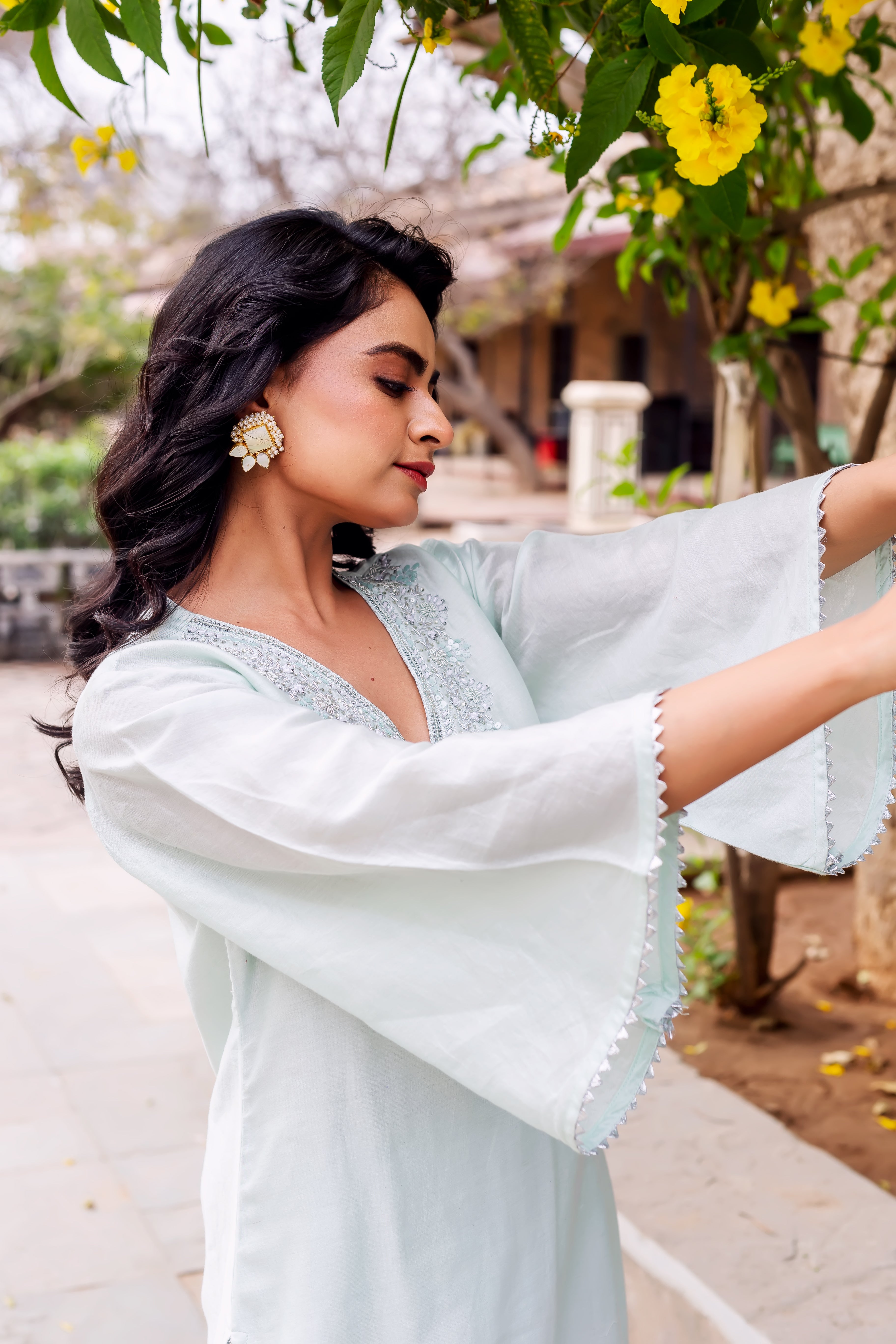 Side view of model in light mint kurta with embroidered V-neck and bell sleeves.