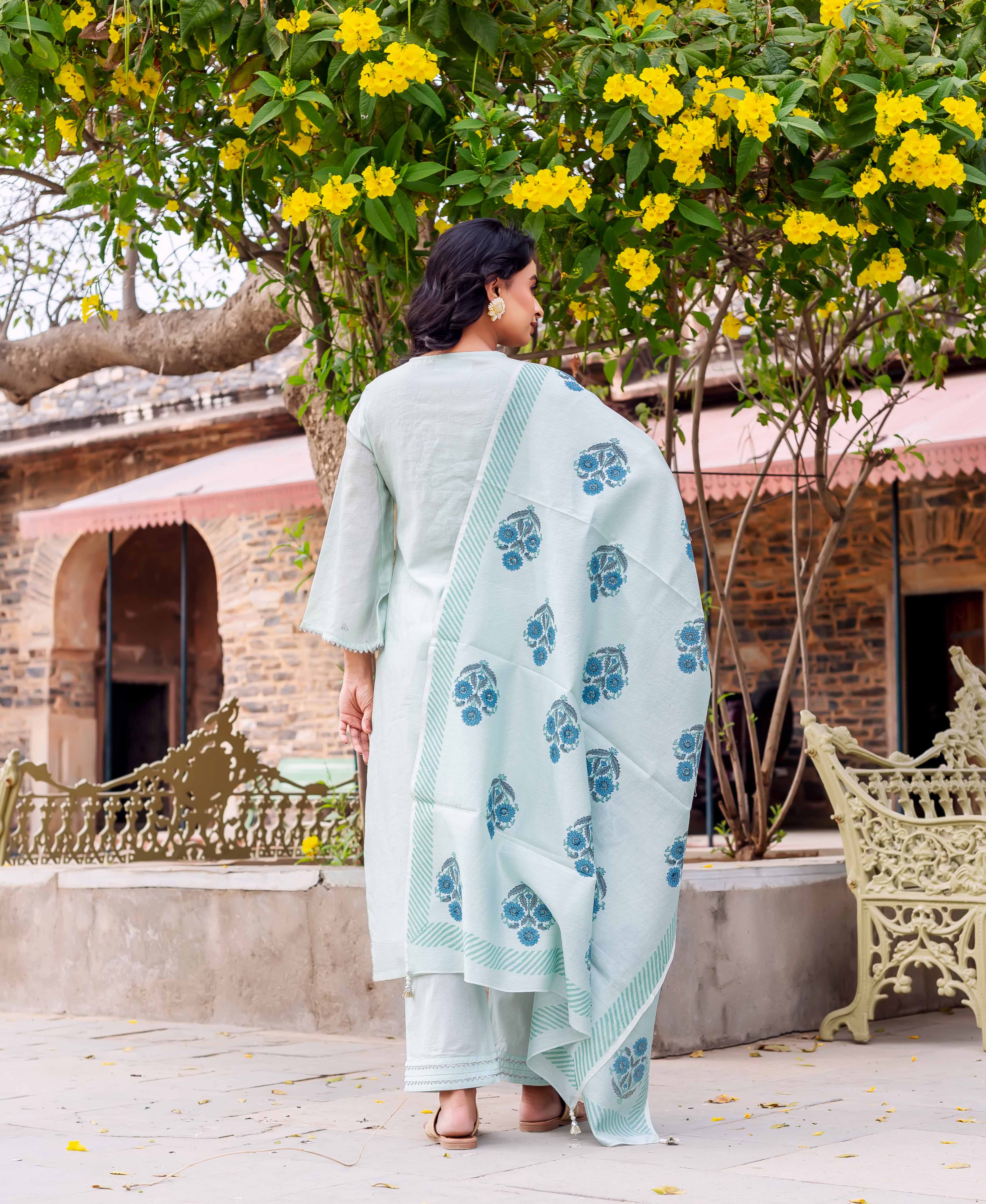 Woman from behind in mint green kurta set, blue floral block print dupatta with striped borders.