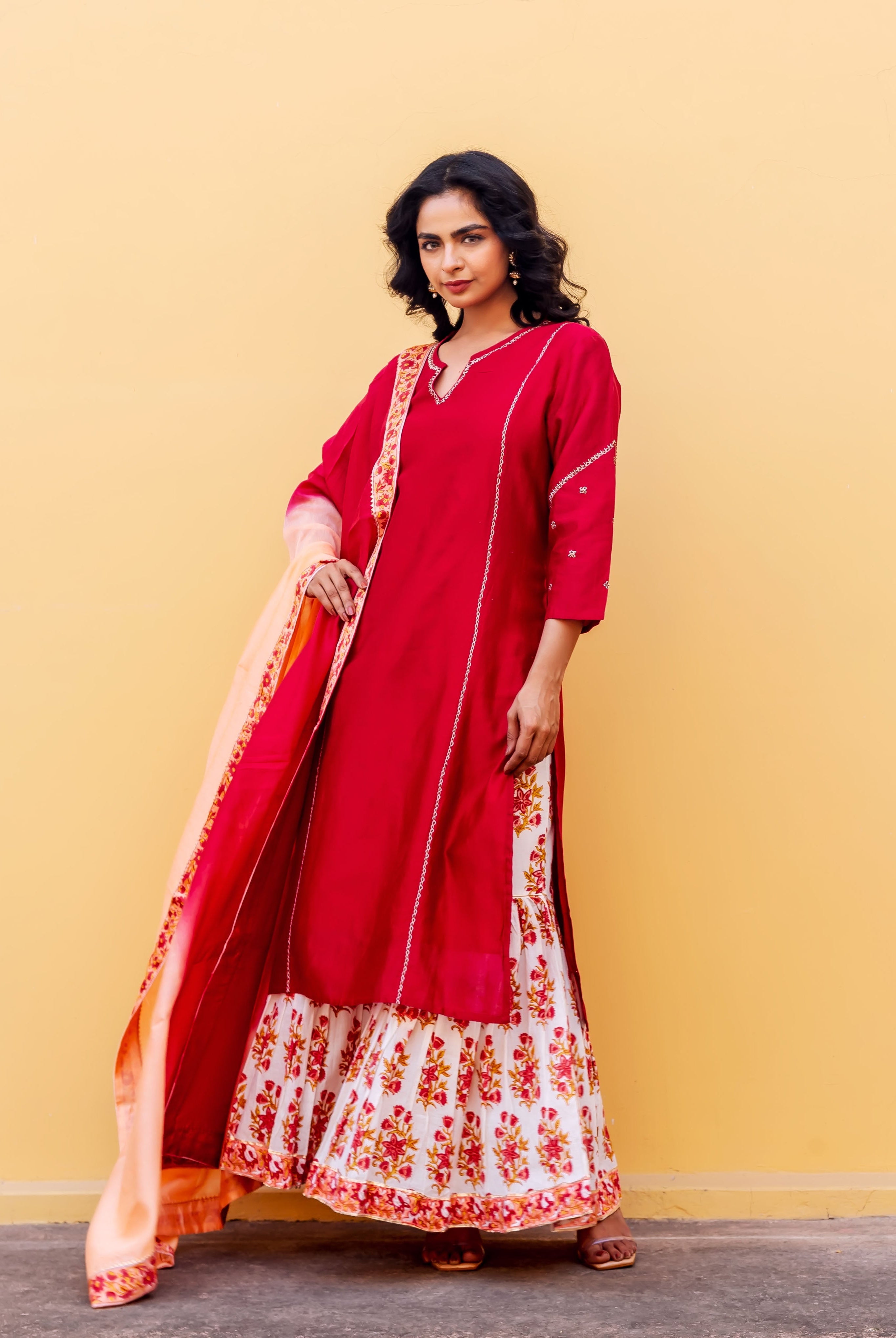 Full-length model in red kurta, white and red floral block-printed sharara, peach dupatta.