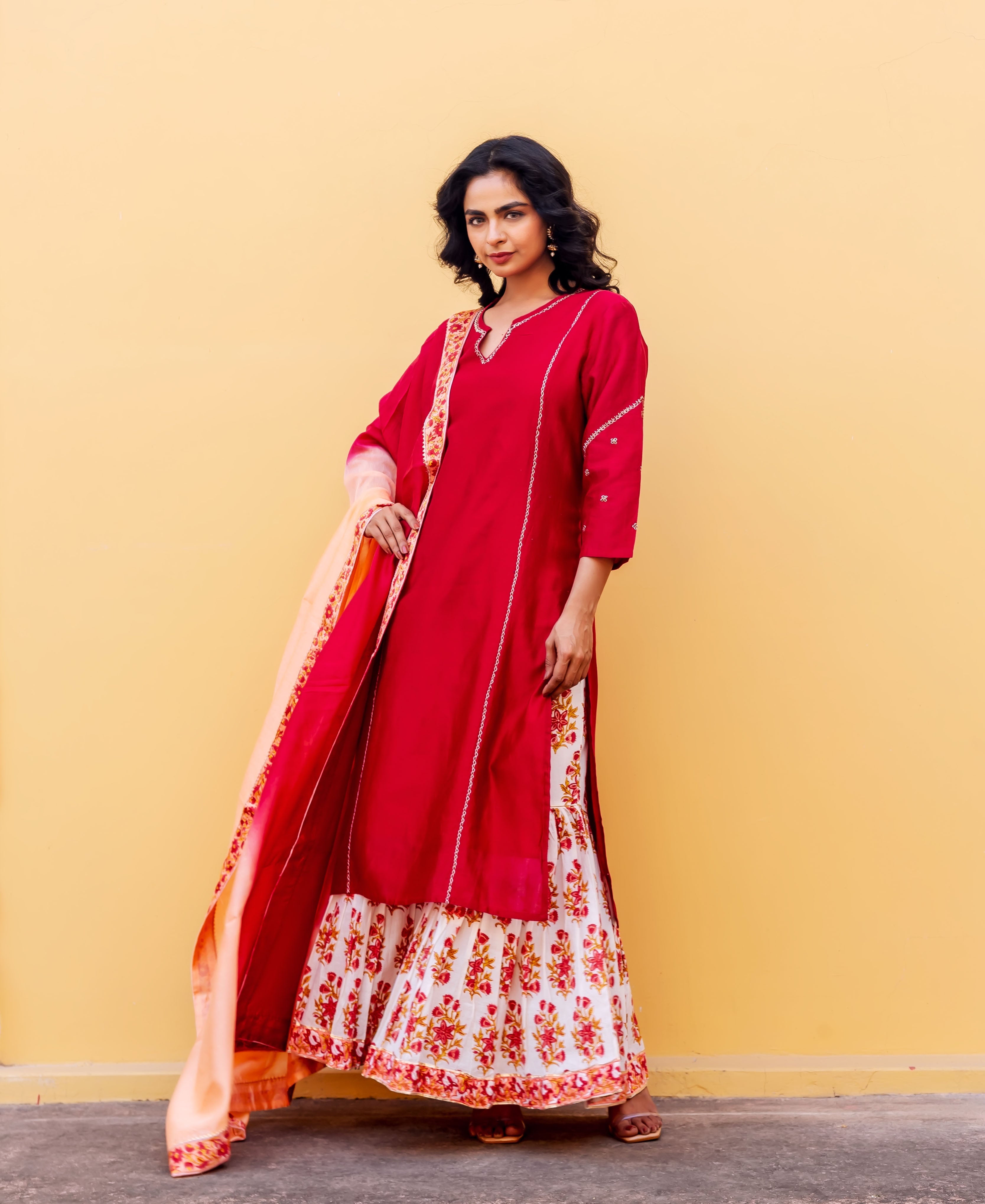 Full-length model in red kurta, white and red floral block-printed sharara, peach dupatta.