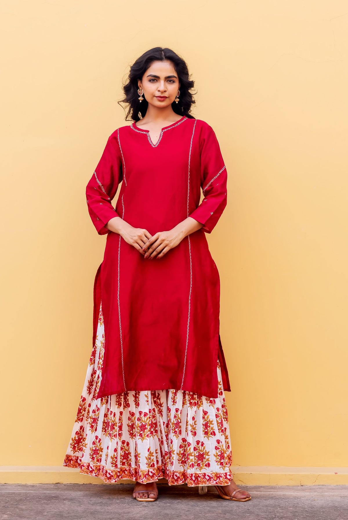 Front-facing model wears red kurta with white stitch detail and white floral hand-block printed skirt.