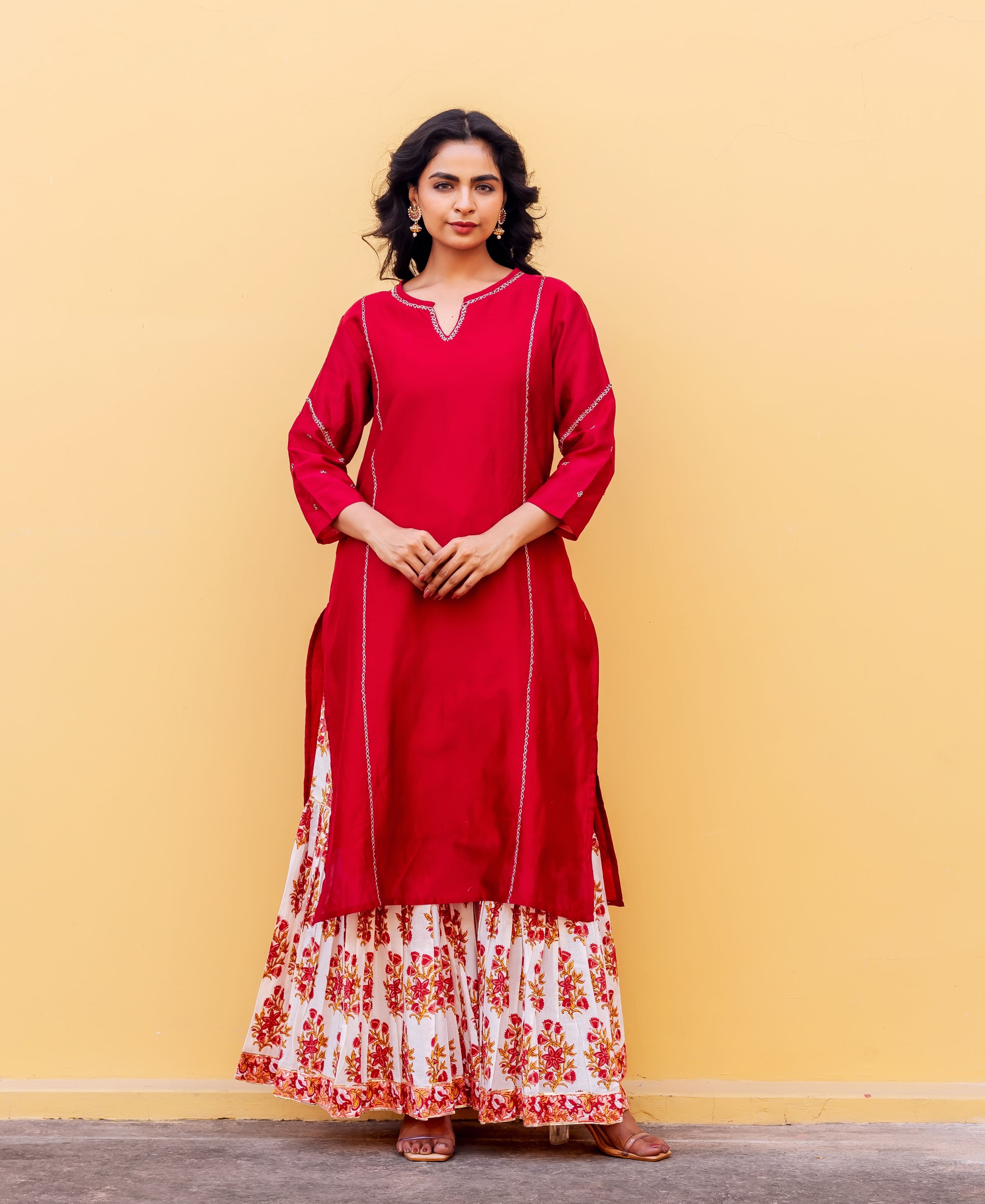Front-facing model wears red kurta with white stitch detail and white floral hand-block printed skirt.
