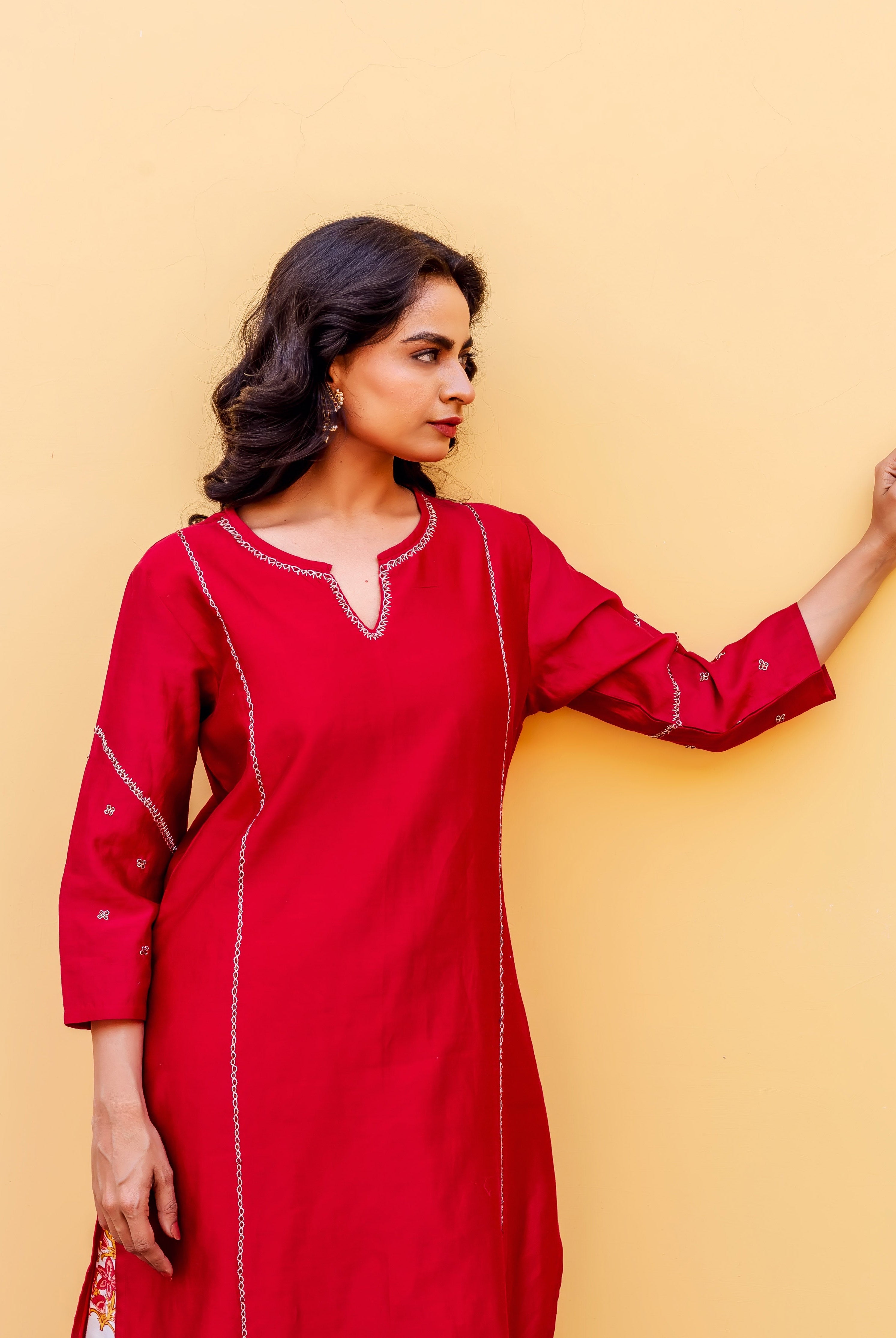 Woman in red kurta with white embroidered trim, side profile, and floral print at hem.