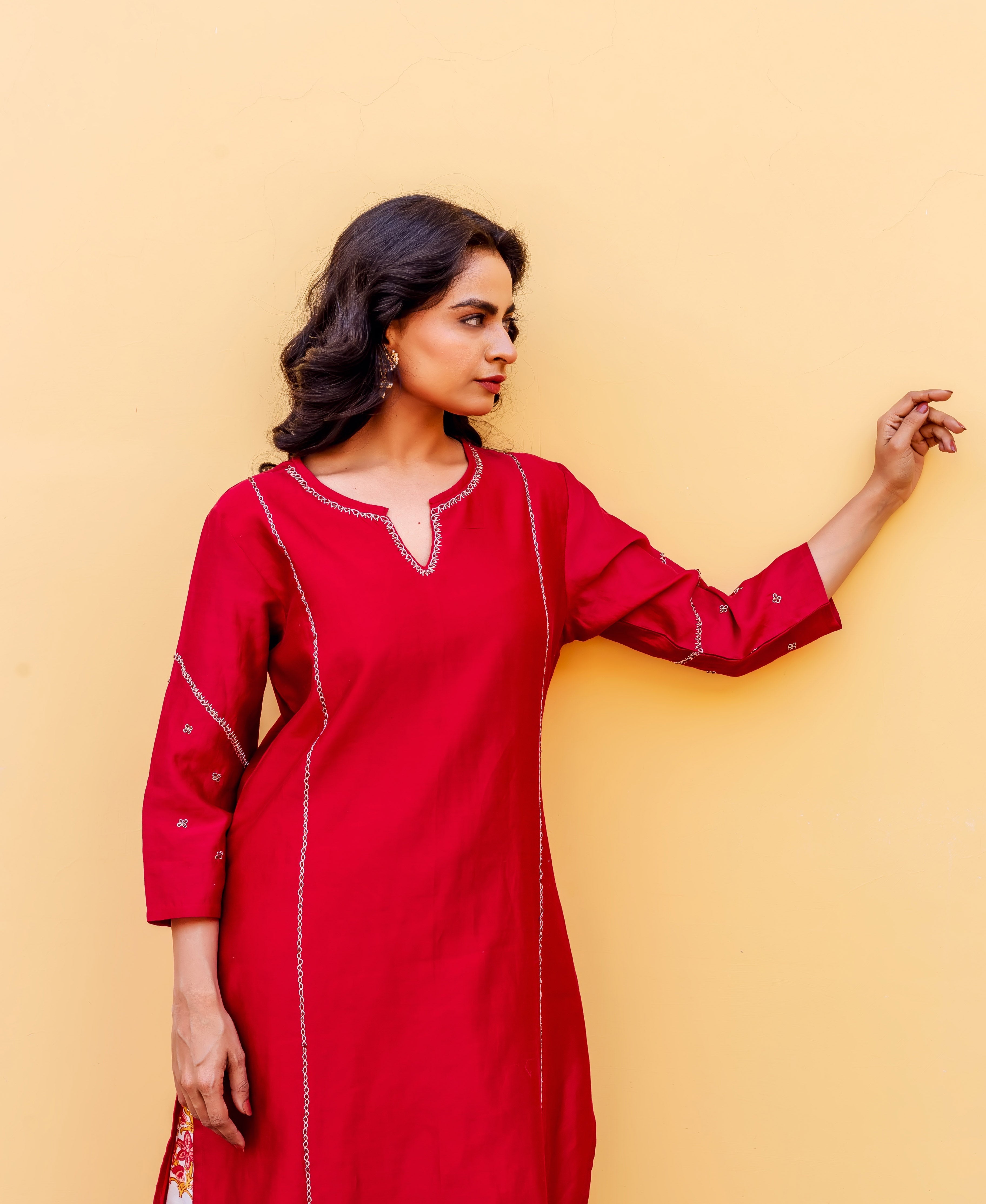 Woman in red kurta with white embroidered trim, side profile, and floral print at hem.
