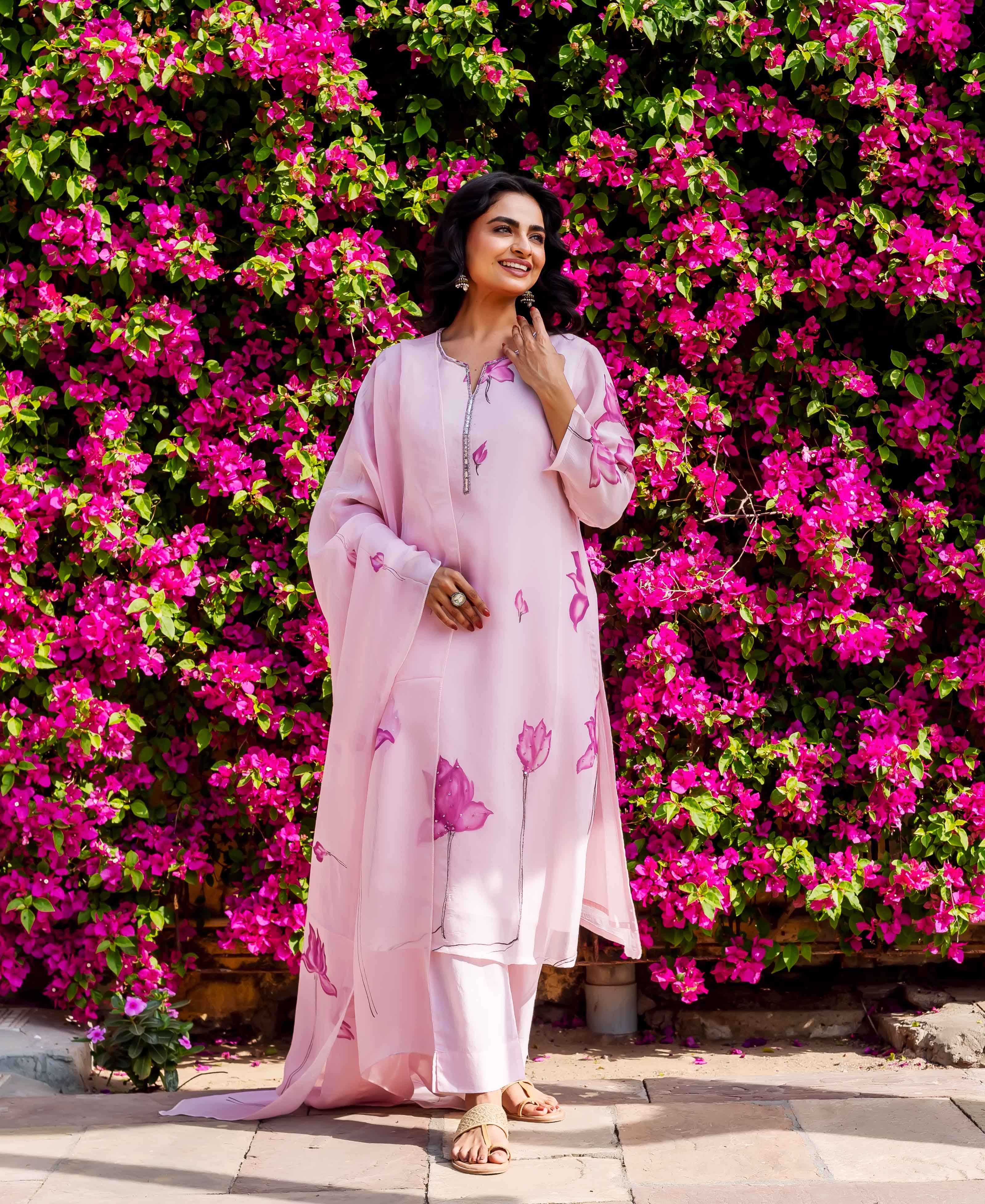 Smiling woman in light pink kurta set with purple floral hand-block prints.