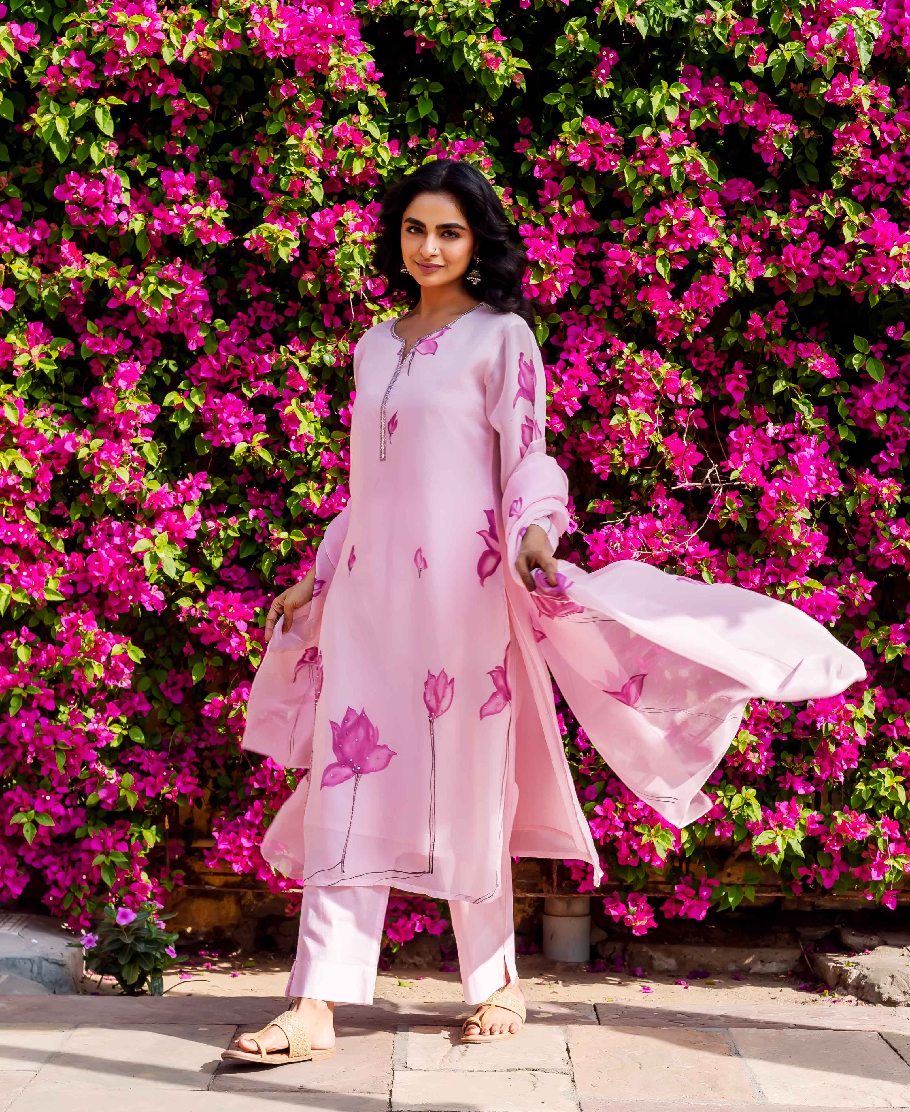 Model wears full pink organza kurta set with hand-block-printed pink lotus designs.