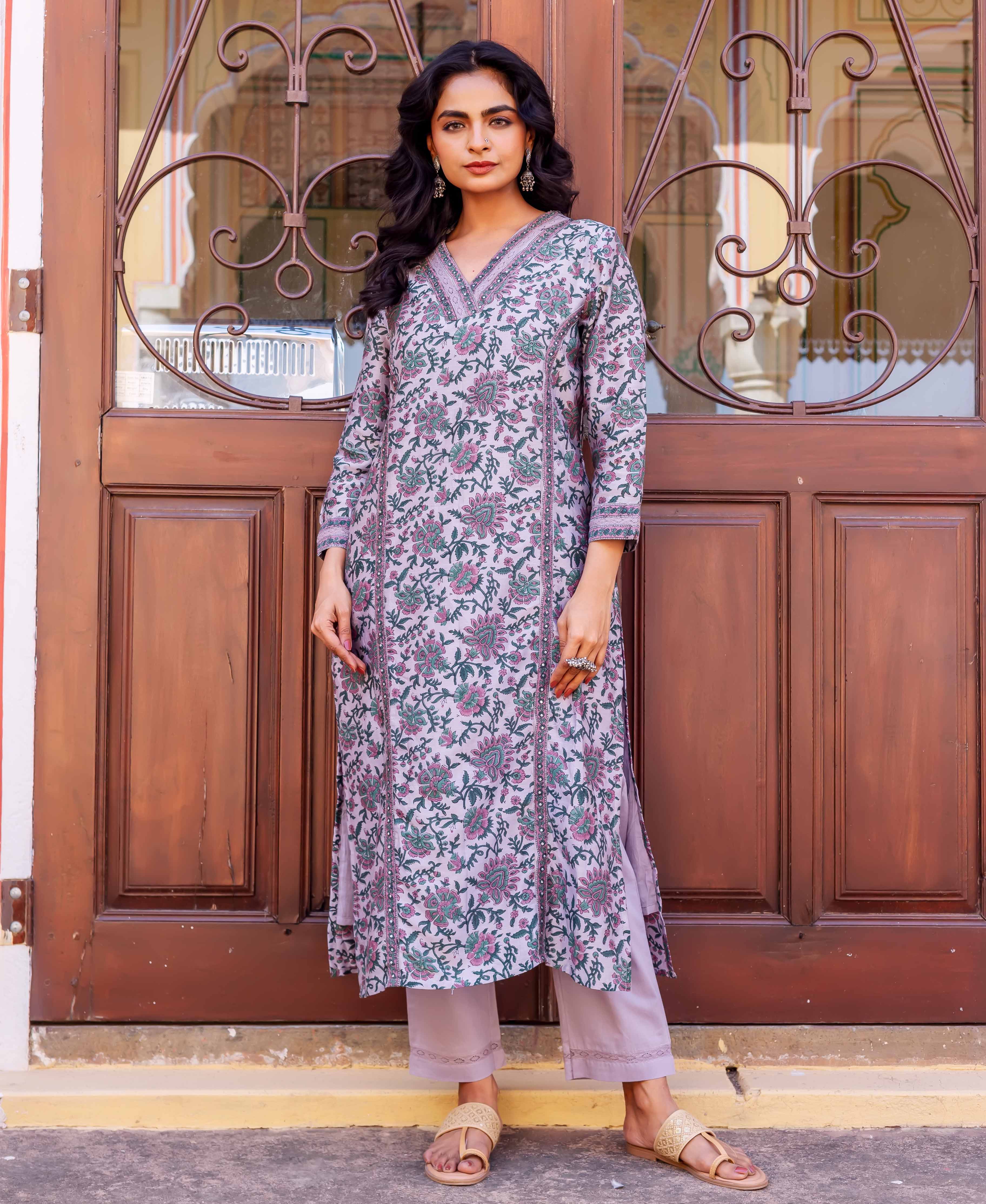Woman wearing long lilac tunic with pink and green floral hand-block print and pale trousers.