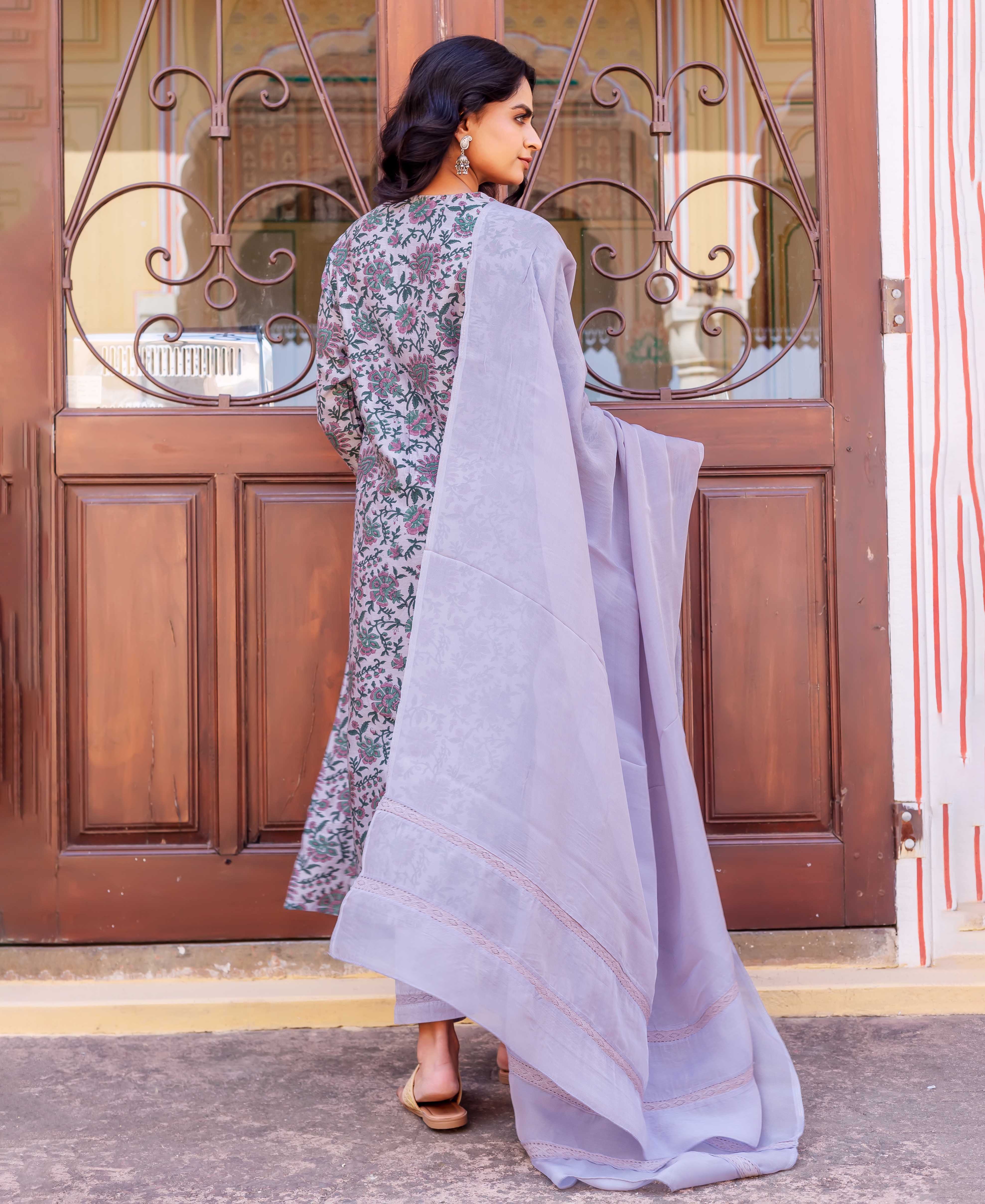Woman from back wearing grey floral block-printed kurta with long sleeves and flowing light purple dupatta.