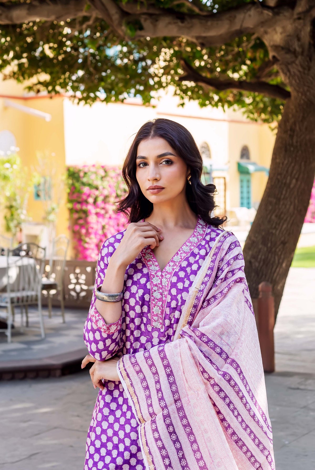 A woman in a purple and white patterned kurta with a matching dupatta.