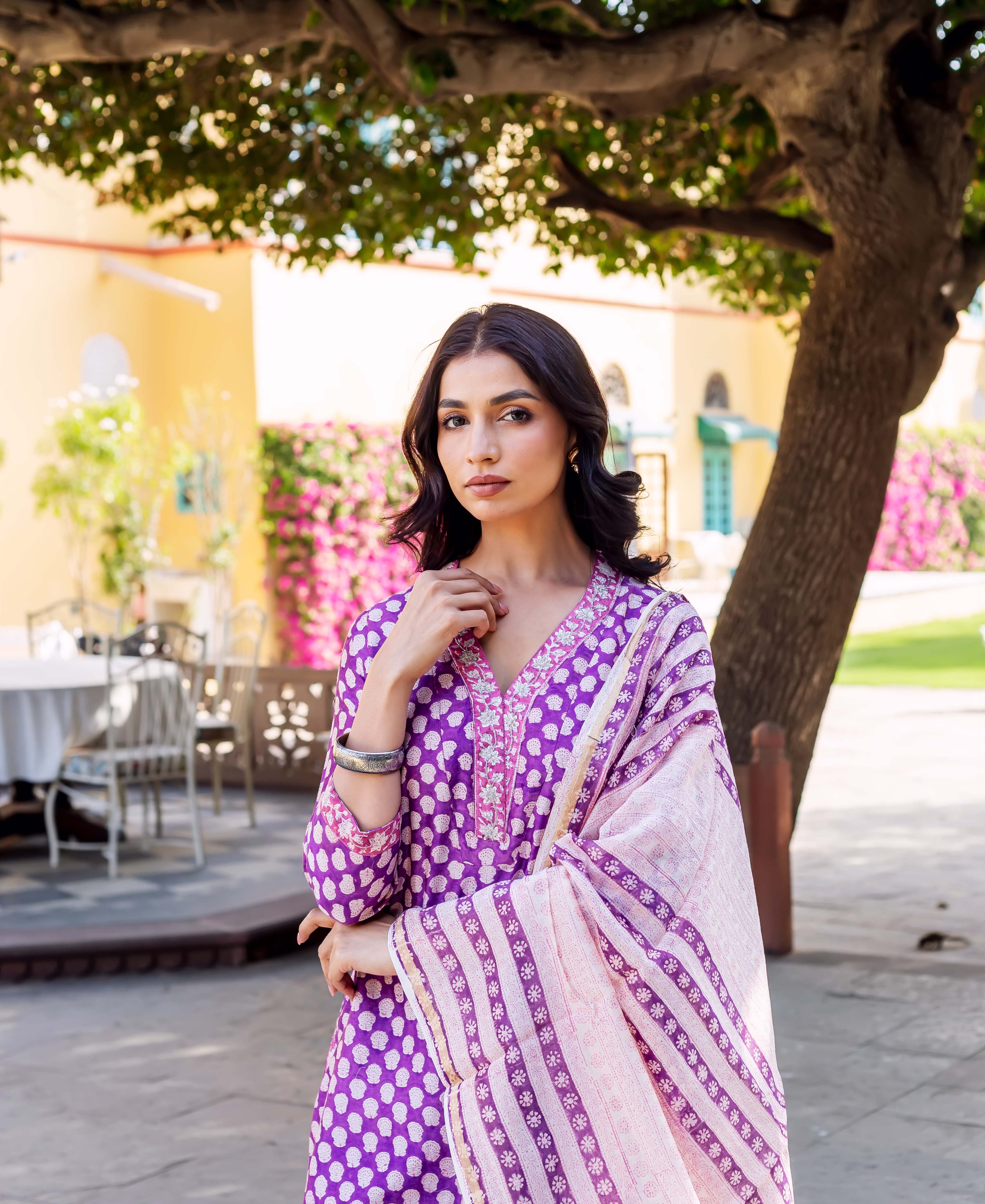 A woman in a purple and white patterned kurta with a matching dupatta.