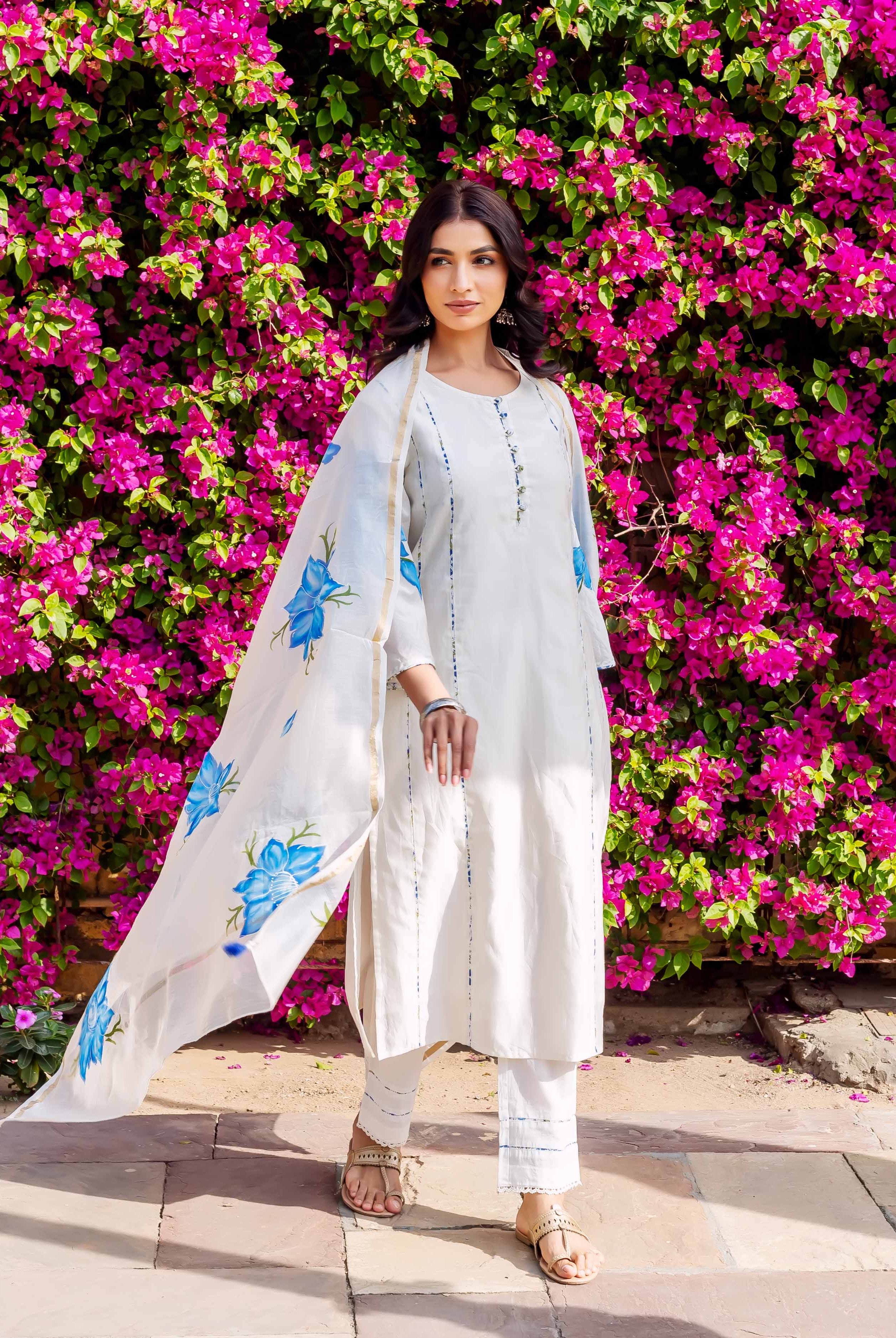 Model in white kurta set with blue brush-painted floral dupatta and subtle vertical lines.