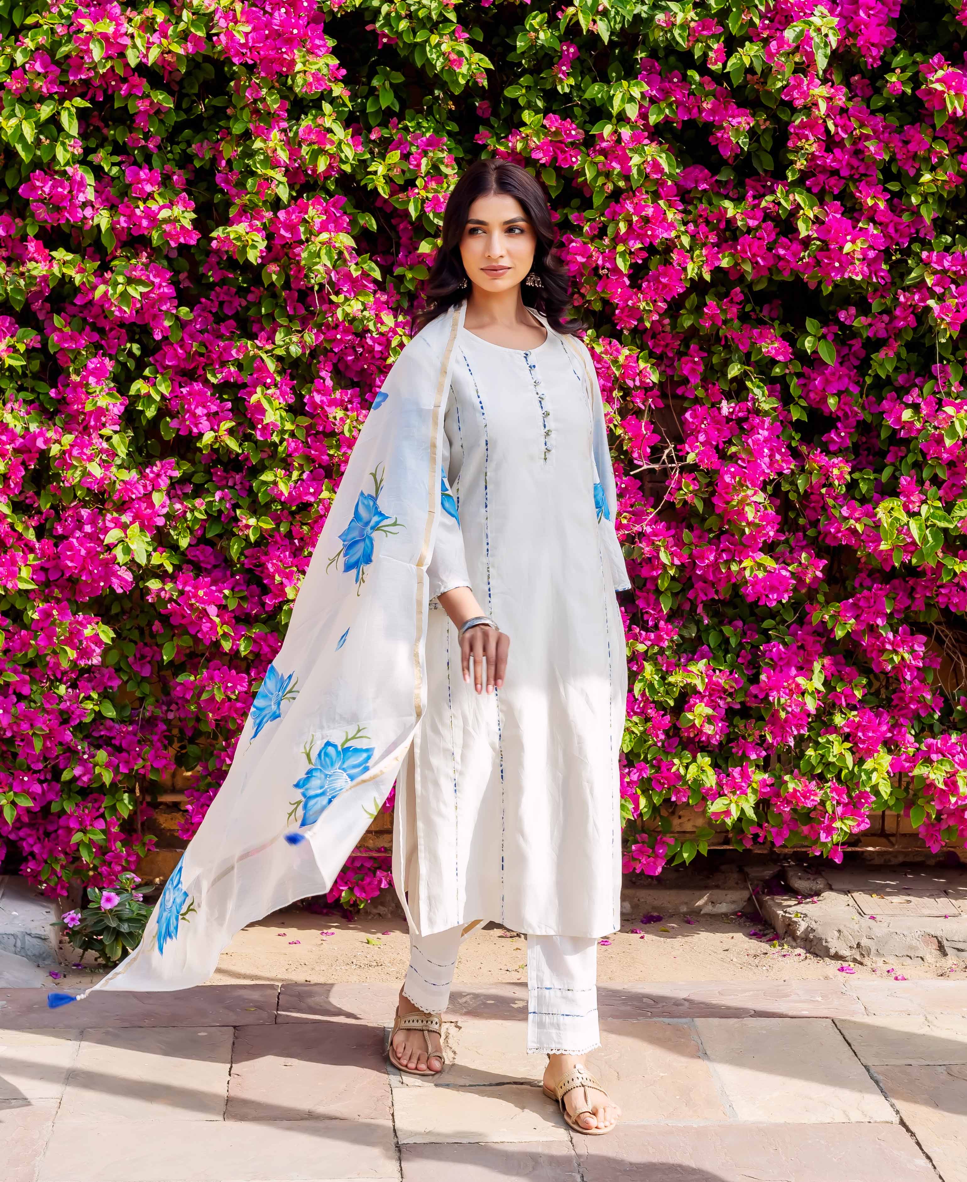 Model in white kurta set with blue brush-painted floral dupatta and subtle vertical lines.