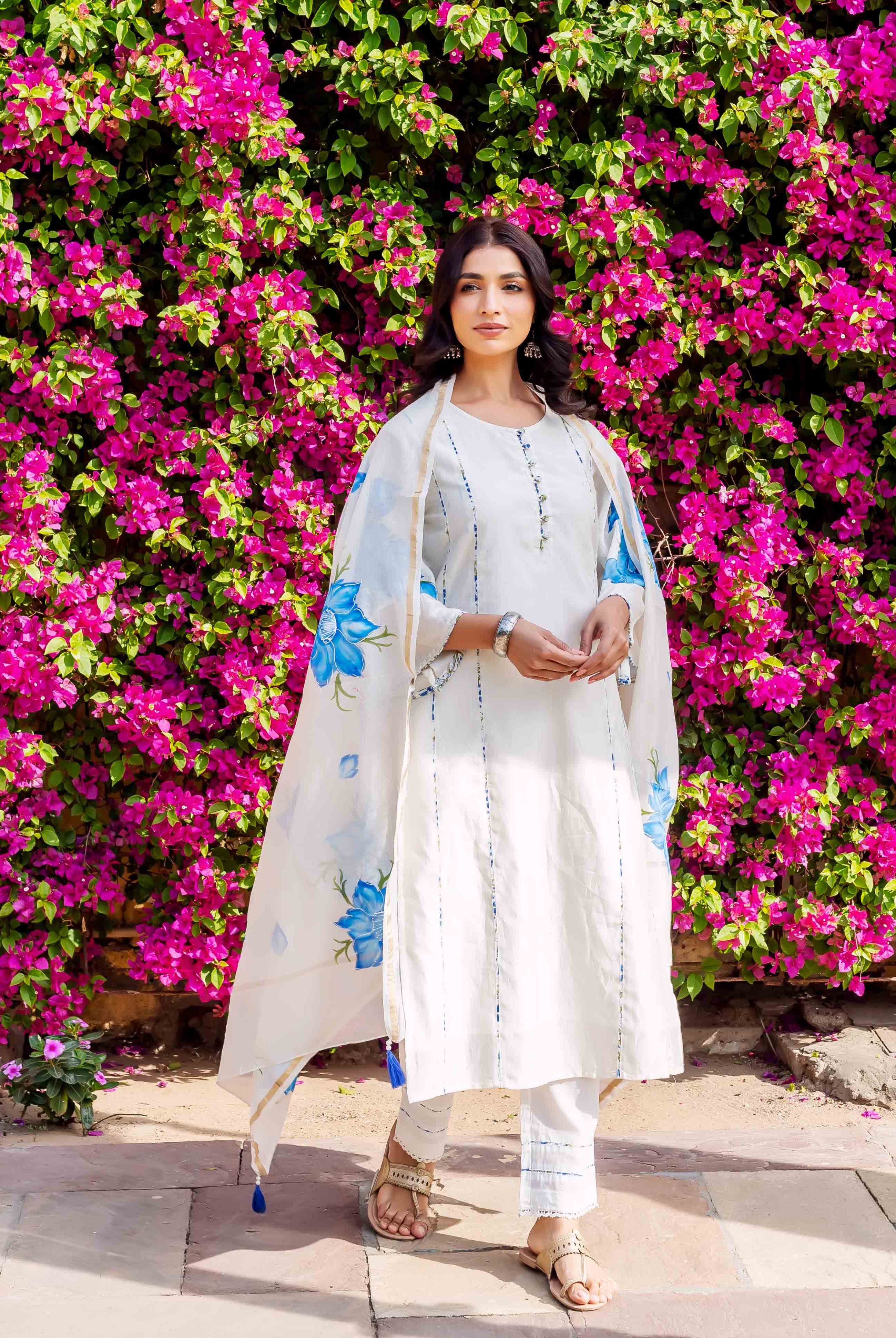 Front view of model in white brush-painted kurta set with blue floral dupatta.
