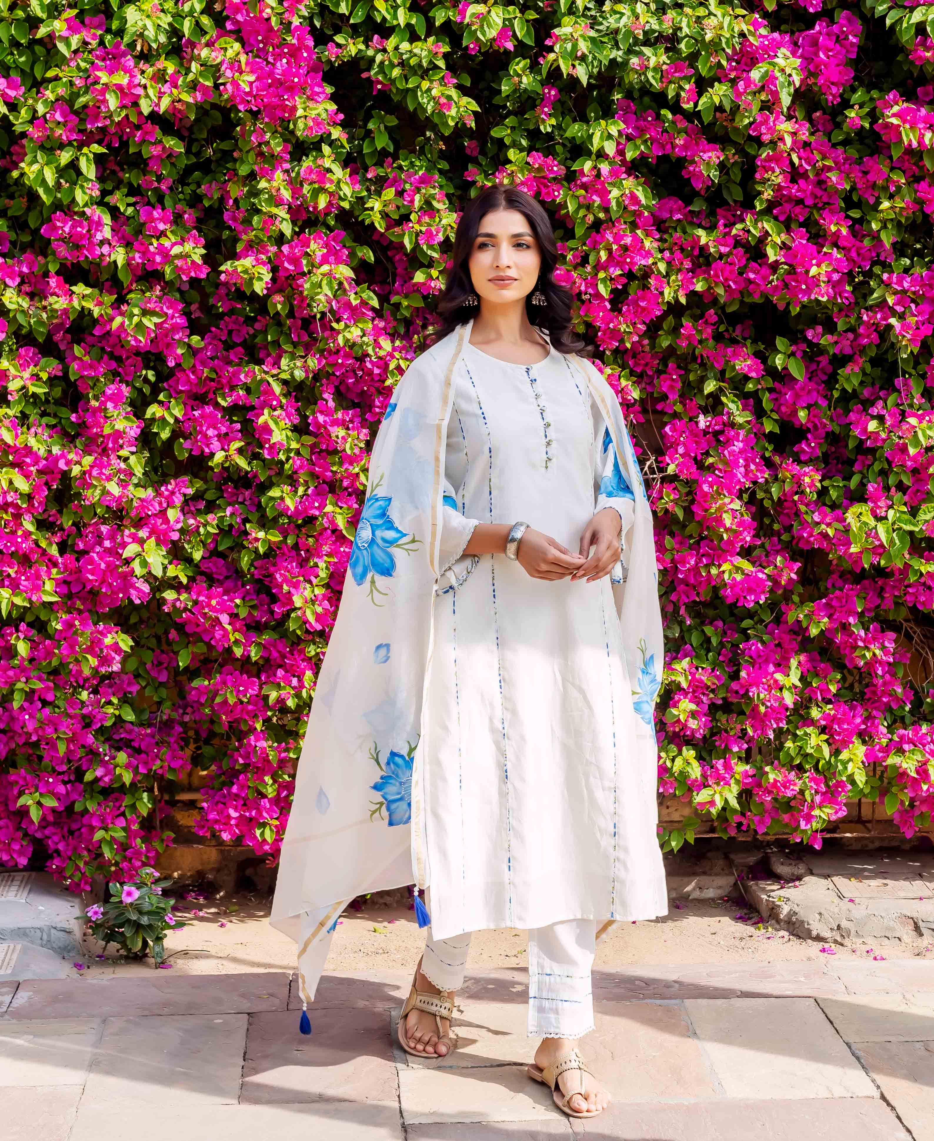Front view of model in white brush-painted kurta set with blue floral dupatta.