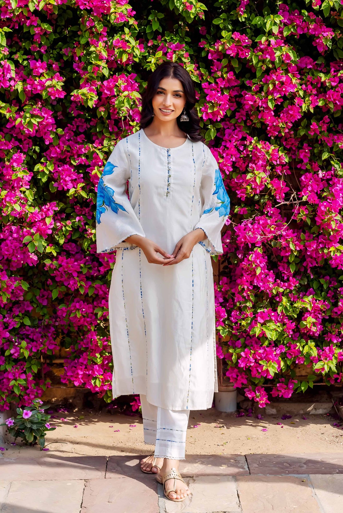 Front view of a model in a white kurta set with blue brush-painted floral sleeves and stripes.