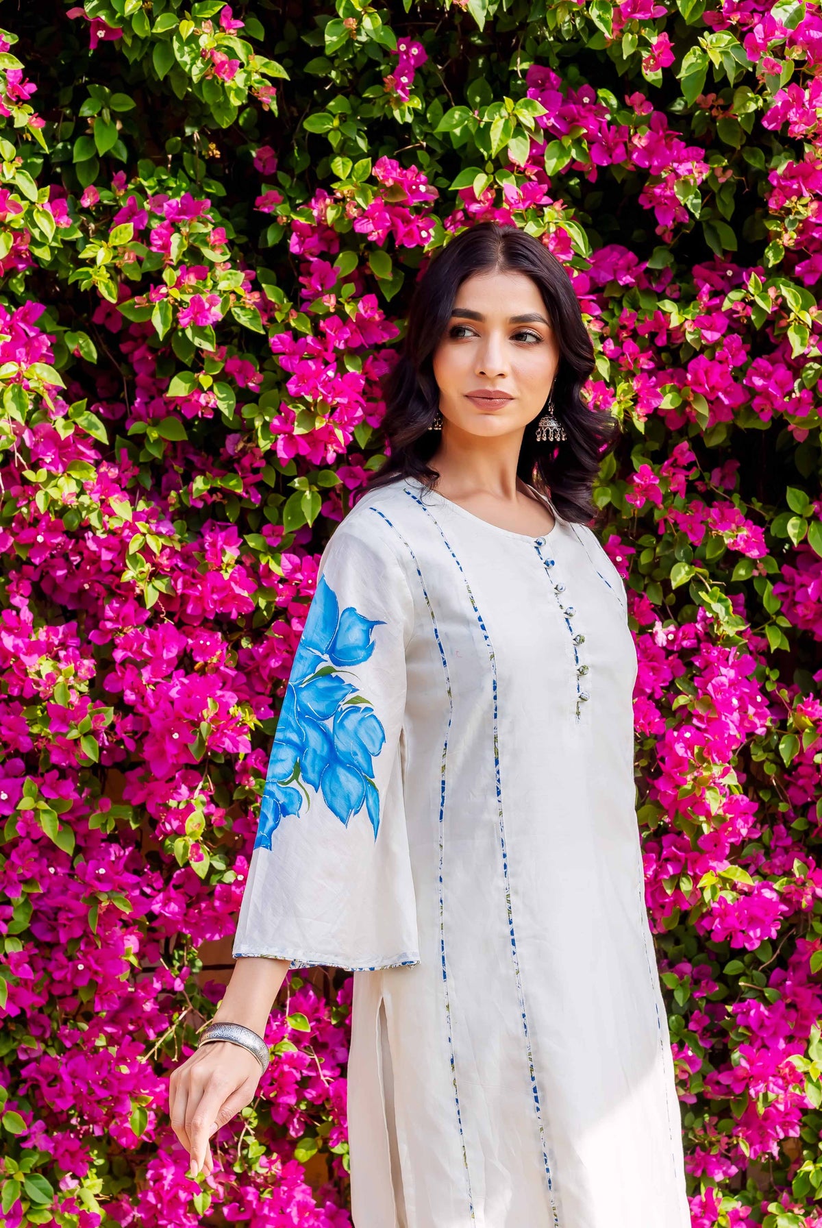 White kurta with blue brush-painted floral sleeves and subtle vertical stripes on model.